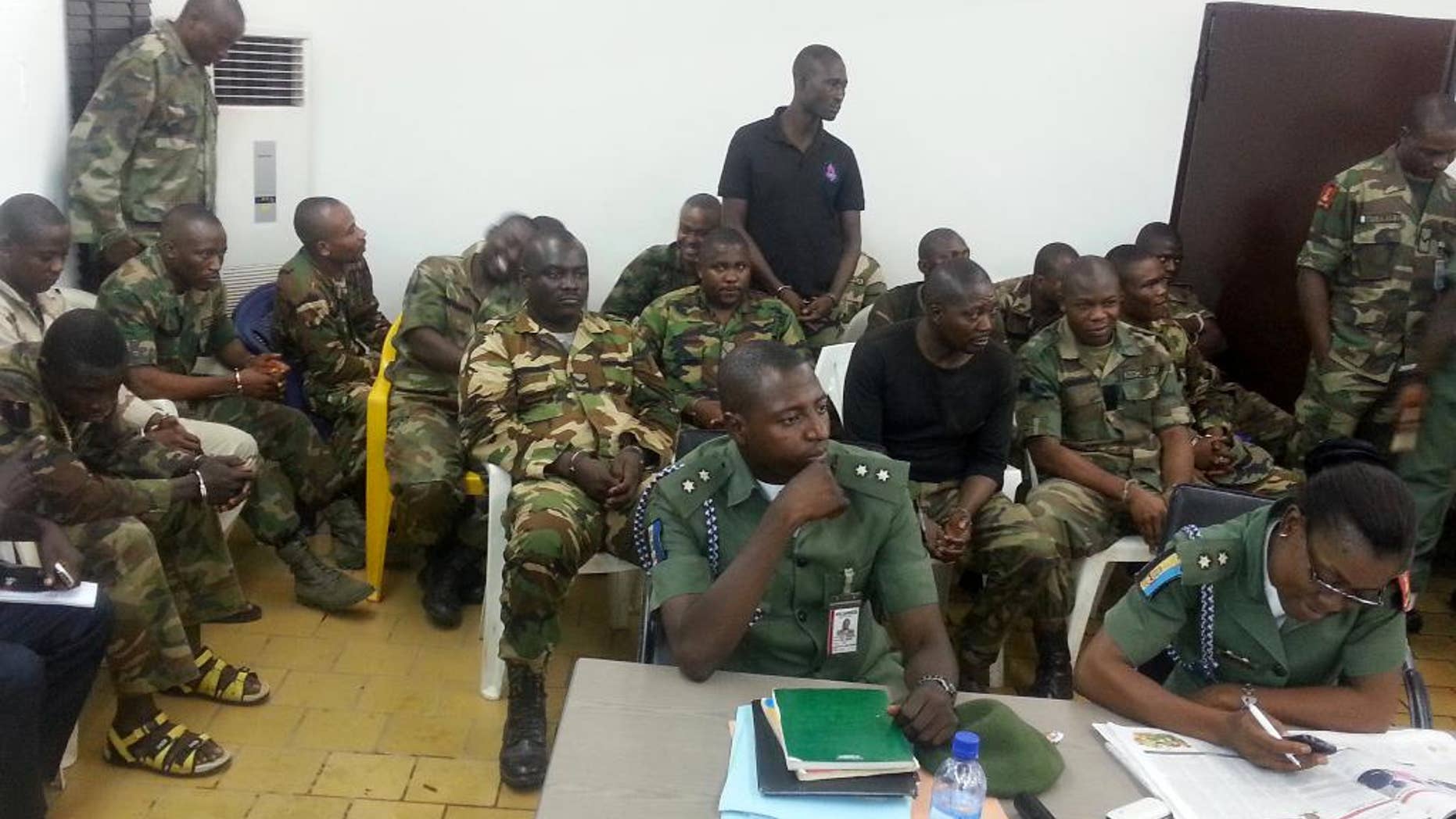 In this photo taken with a mobile phone Tuesday, Sept. 16. 2014 in Abuja Nigeria. Unidentified military prosecutors sit in the front row, while soldiers accused of an attack on their commander appear before a court martial in Abuja. Twelve soldiers fighting an Islamic insurgency in northeast Nigeria have been sentenced to death by firing squad for mutiny and attempted murder of their commanding officer. In a decision read early Tuesday by Brig. Gen. Chukwuemeka Okonkwo, the military tribunal found 12 soldiers guilty and five others innocent. One was sentenced to 28 days in jail with hard labor. ( AP Photo)