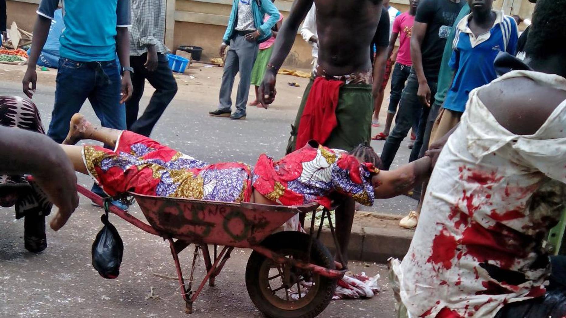 EDITORS NOTE GRAPHIC CONTENT An injured woman is carried after bombs exploded at a bus terminal and market in Jos, Nigeria, Tuesday, May 20, 2014. Two car bombs exploded at a bustling bus terminal and market in Nigeria's central city of Jos on Tuesday, and witnesses said dozens of people were killed. No one immediately claimed responsibility for the twin car bombs, but they bore the hallmarks of Boko Haram, an Islamic extremist group. (AP Photo/Stefanos Foundation)