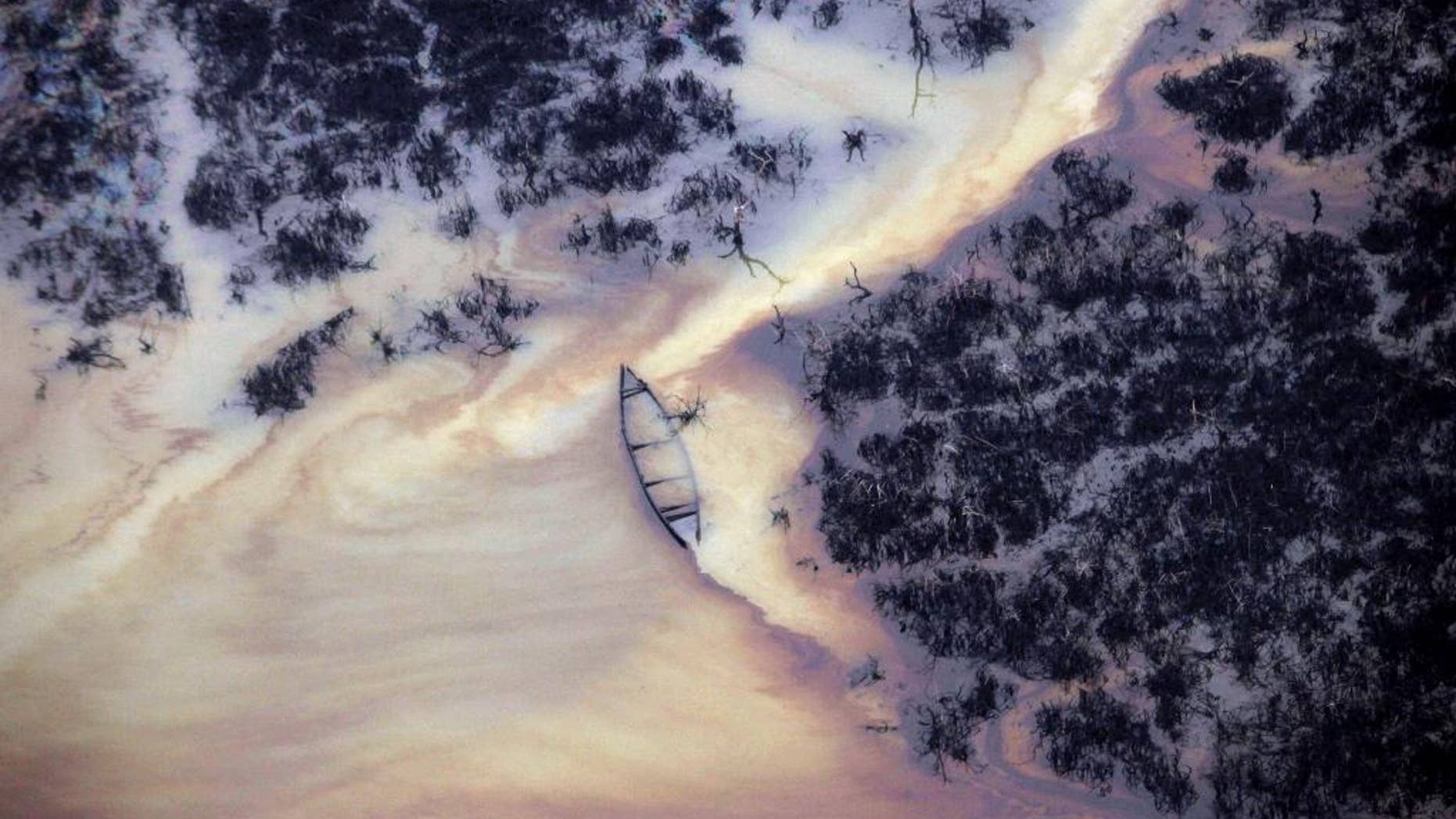 FILE - In this March 24, 2011 file photo, oil is seen on the creek water's surface near an illegal oil refinery in Ogoniland, outside Port Harcourt, in Nigeria's Delta region. Amnesty International says oil giant Shell's claims of cleaning up spills that have destroyed the livelihoods of hundreds of thousands of Nigerians are "false." A report issued Tuesday Nov. 3, 2015 quotes one contractor as saying his clean-up was "a cover-up." (AP Photo/Sunday Alamba, File)