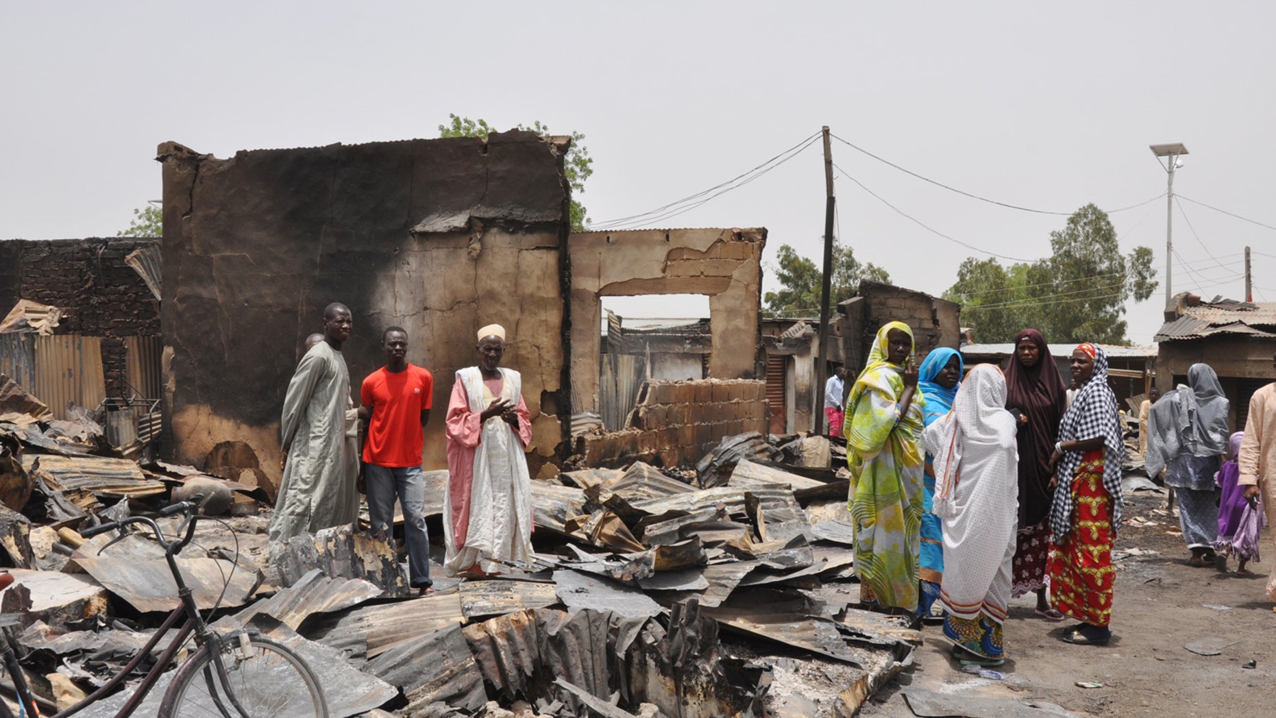 May 11, 2014 - People stand outside burnt houses following an attack by Islamic militants in Gambaru, Nigeria. Many brutalized residents of the once bustling town of Gamboru say they are moving across the border to Cameroon because they cannot trust the Nigerian government to protect them.