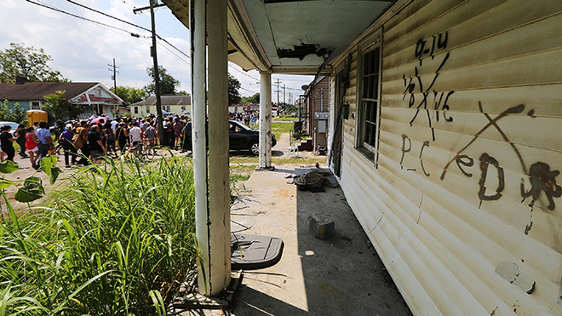 NEW ORLEANS, LA - AUGUST 29: Revelers march past an abandoned home still marked by rescue markings in the Lower Ninth Ward during a second line parade marking the 10th anniversary of Hurricane Katrina on August 29, 2015 in New Orleans, Louisiana. A levee breach along the Industrial Canal in the Lower Ninth Ward devastated the area with massive flooding in the aftermath of Hurricane Katrina. (Photo by Mario Tama/Getty Images)