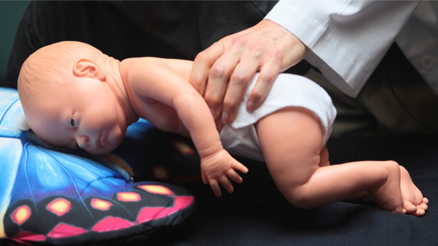 FILE- In this March 22, 2012 file photo, Dr. Wendy Gunther demonstrates how an infant can die due to unsafe sleeping practices using a scene re-enactment doll in Norfolk, Va. (AP Photo/The Virginian-Pilot, Steve Earley, File)