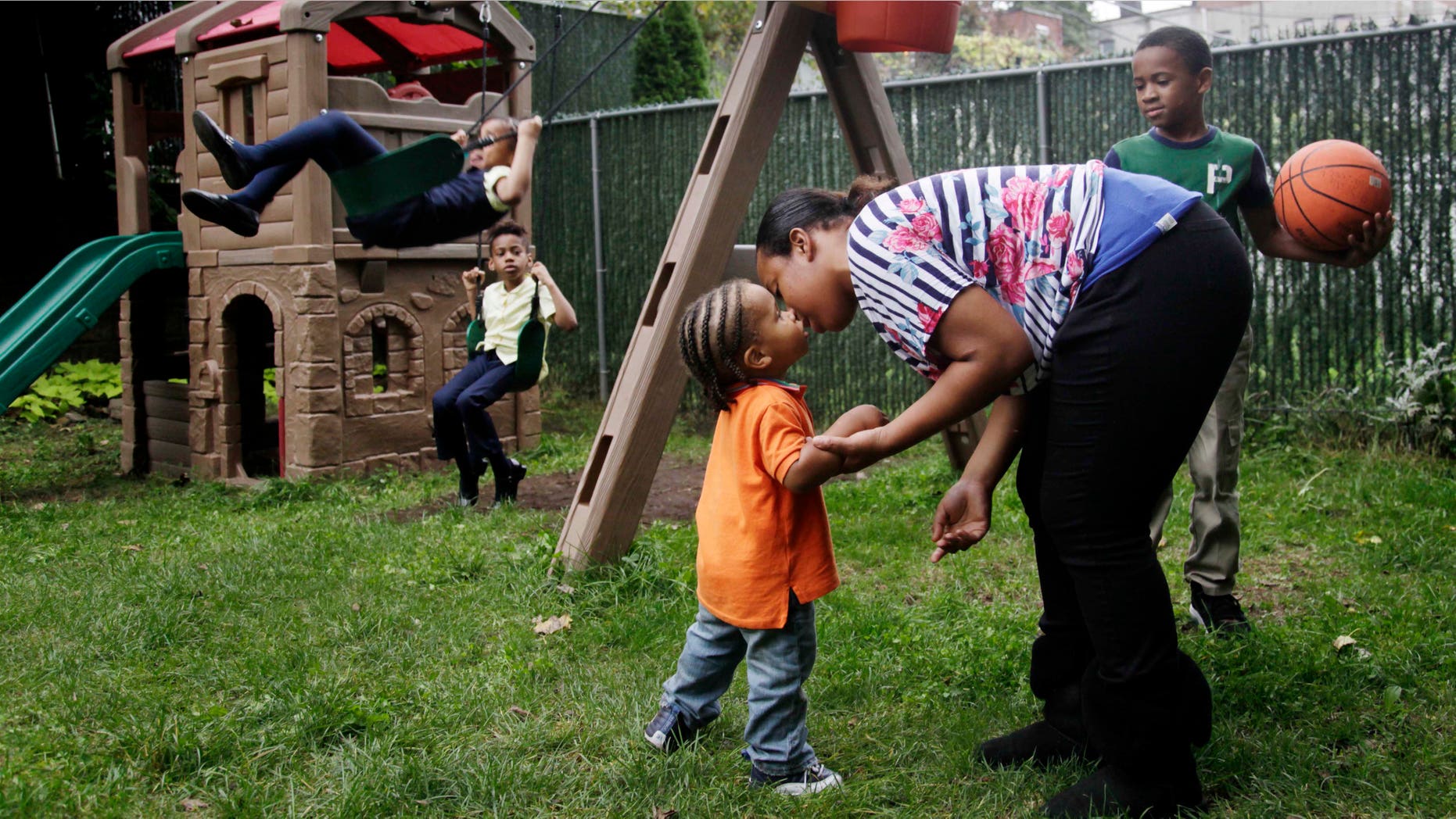 Olgita Blackwood kisses her son, Omarhie Blackwood, 1, in the yard for the Drew House in New York, Wednesday, Oct. 3, 2012. The program, called Drew House, is one of a kind in the nation, where mothers arrested on felonies can live with their children, instead of in prison. The program has been lauded as a success that should be replicated around the country, but the small house is already full, and without additional funding and space, it canât grow. (AP Photo/Seth Wenig)