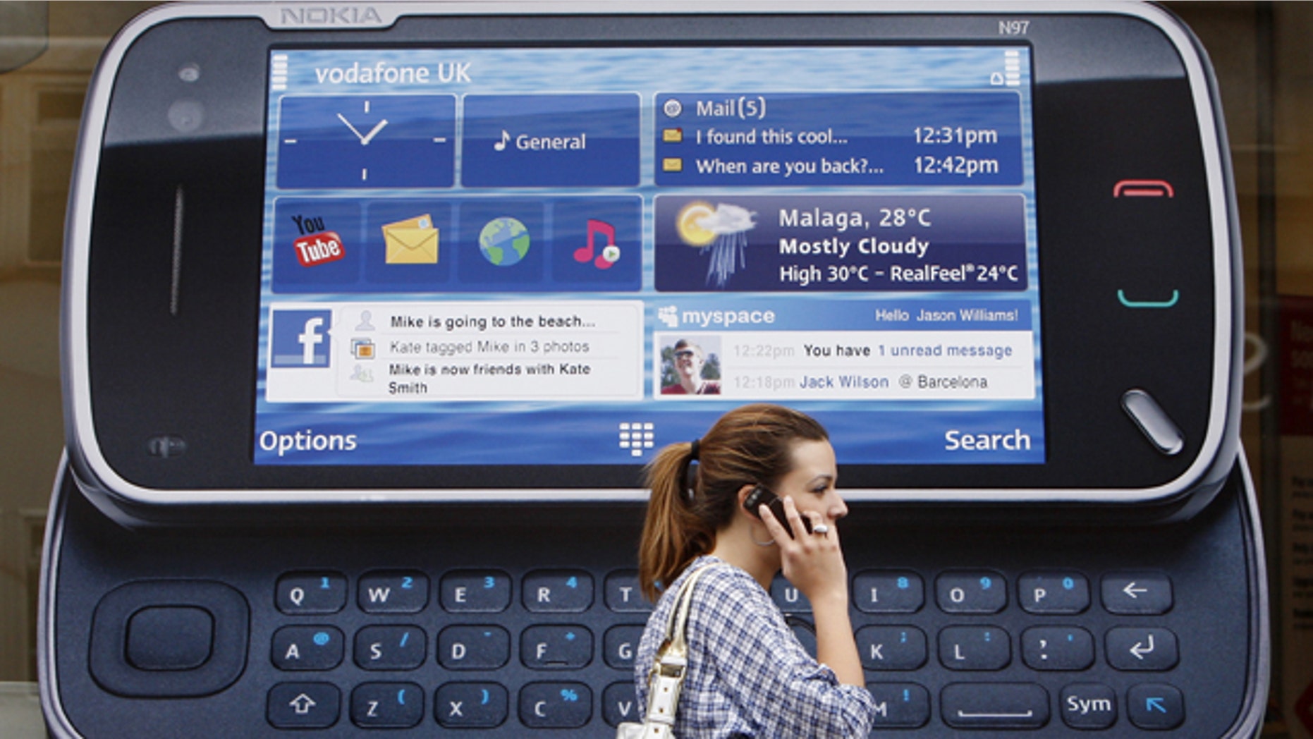 A woman uses her mobile telephone as she passes a Nokia advert in London.