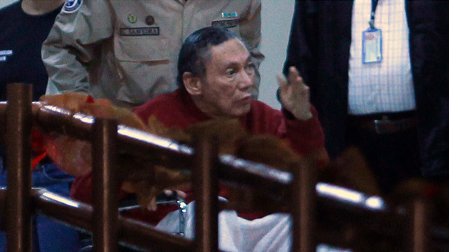 FILE - In this Dec. 11, 2011, file photo, Panama's ex-dictator Manuel Noriega gestures while being carried in a wheelchair by a police officer inside El Renacer prison in the outskirts of Panama City. Speaking to local television network the former Panamanian strongman broke his long silence in a interview from jail, aired on Wednesday, June 24, 2015, asking his compatriots to forgive actions by the military that culminated in the 1989 American invasion. (AP Photo/Esteban Felix, File)