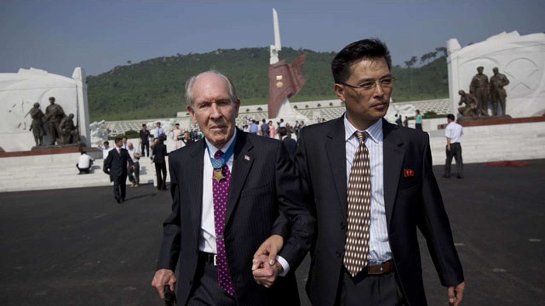 July 25, 2013: Retired U.S. Navy captain and Korean War veteran Thomas Hudner, left, is escorted by a North Korean official as he leaves a cemetery for Korean War veterans after a ceremony marking the 60th anniversary of the signing of the armistice that ended hostilities on the Korean peninsula. (AP PHOTO)