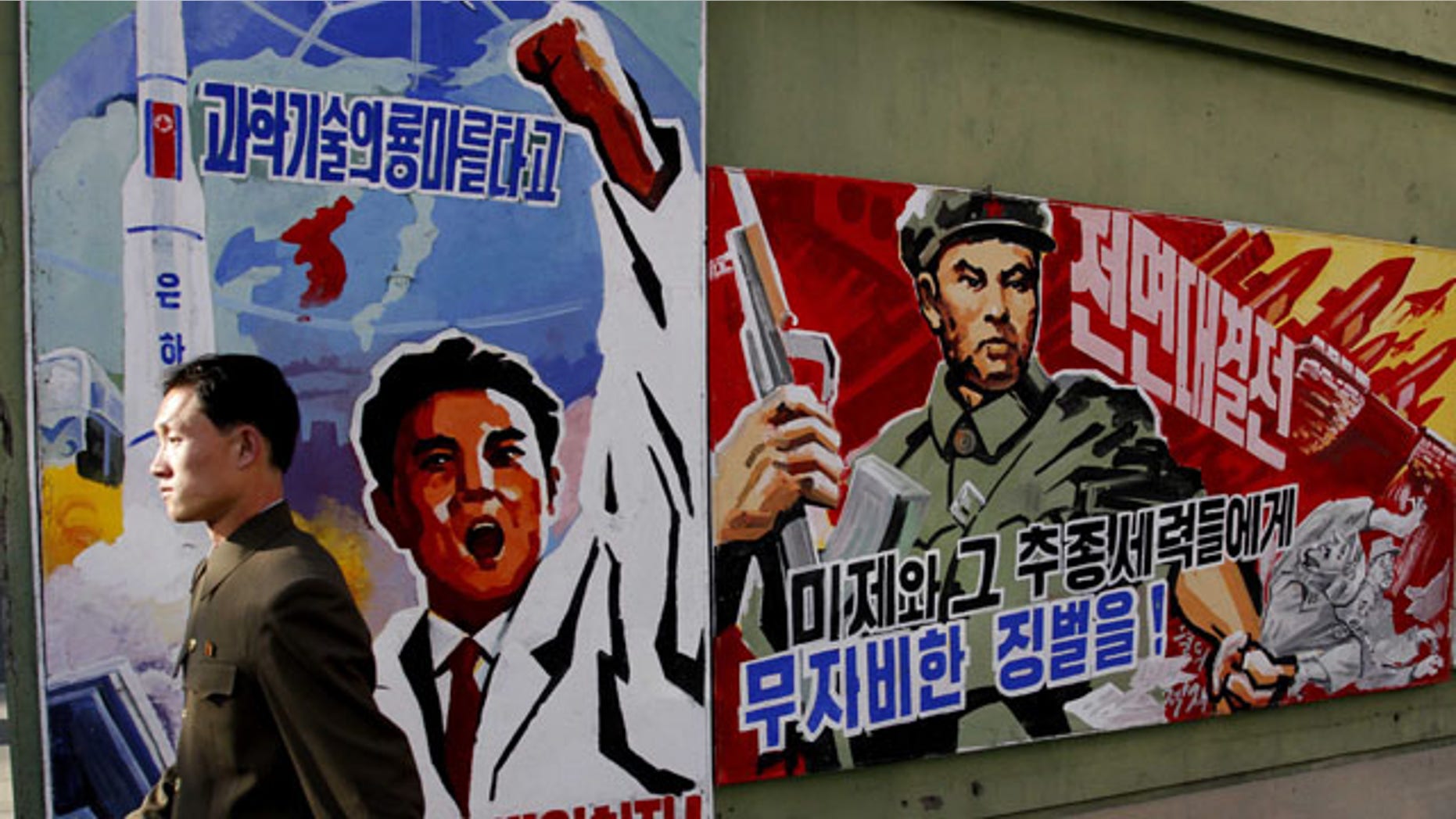 FILE - In this March 26, 2013 file photo, a North Korean man walks past propaganda posters in Pyongyang, North Korea, that threaten punishment to the "U.S. imperialists and their allies." (AP Photo/Kim Kwang Hyon, File)
