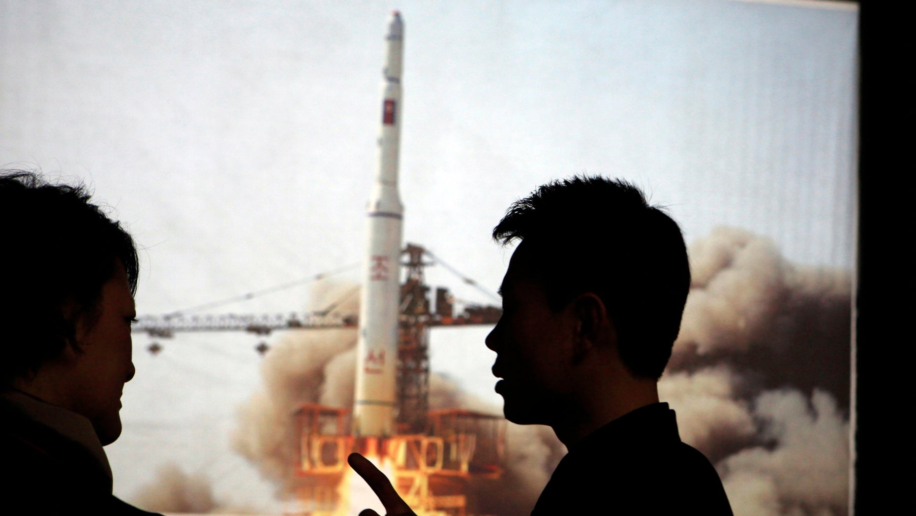 April 10, 2012: In this photo North Korean guide Kim Won Ho, right, speaks to a foreign journalist near a photo depicting the 2009 satellite rocket launch at the Three Revolutions exhibition hall in Pyongyang, North Korea.