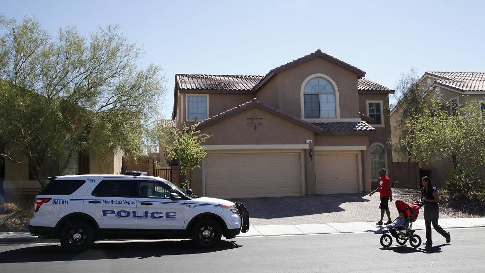 Sheldon Jacobs and his wife Nicole Jacobs walk in front of a home on the 6100 block of Stibor Street in North Las Vegas on Tuesday, April 1, 2014. Police in North Las Vegas think a family member may be responsible for a double-slaying at this home where officers sent to check on a missing 53-year-old mother and her 33-year-old daughter found a bloody crime scene. (AP Photo/Las Vegas Review-Journal, Justin Yurkanin) LOCAL TV OUT; LOCAL INTERNET OUT; LAS VEGAS SUN OUT