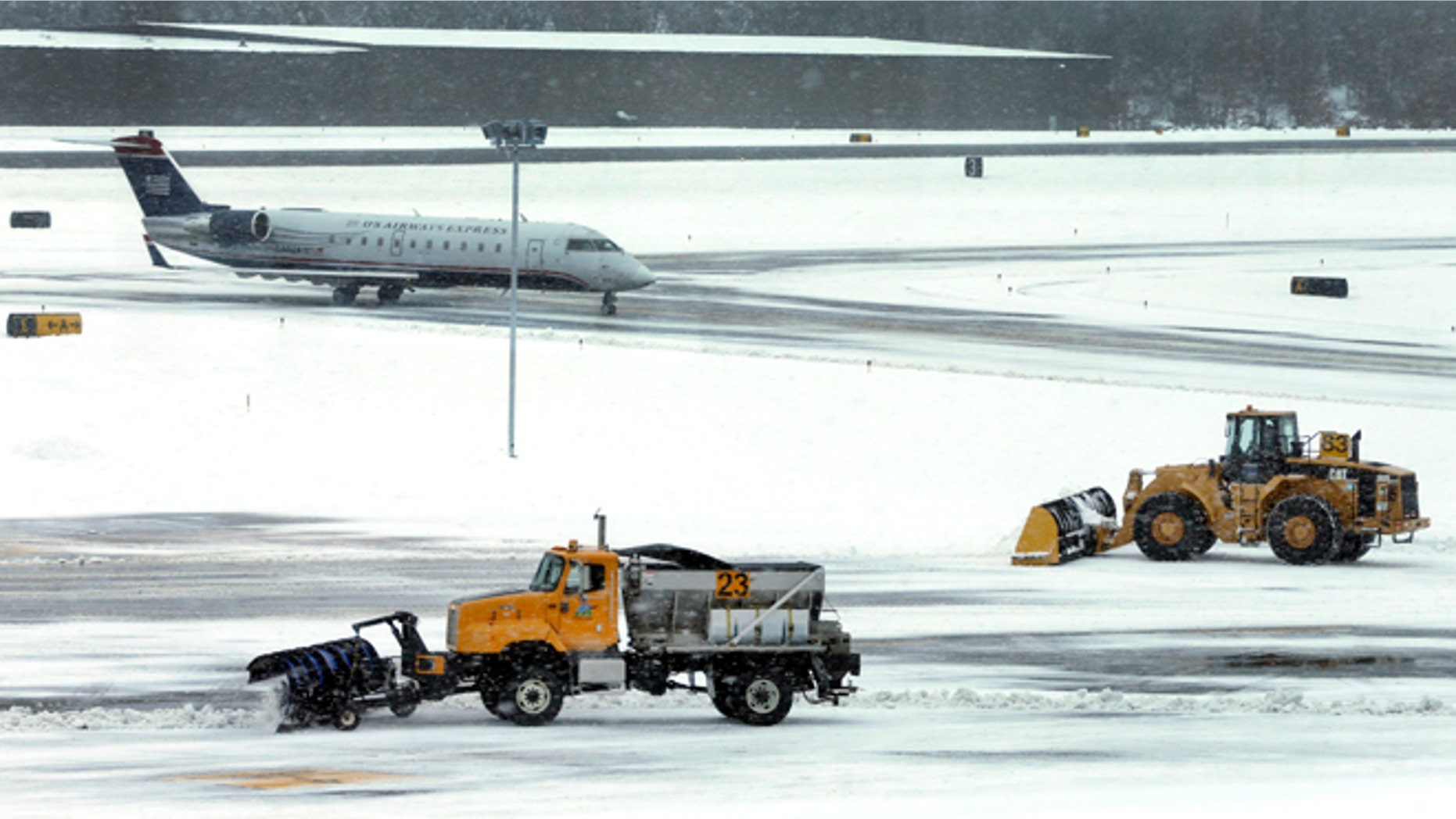 FILE - In this Thursday, Dec. 27, 2012 file photo, snow is cleared on a runway as a plane taxis into Manchester-Boston Regional Airport in Manchester, N.H.