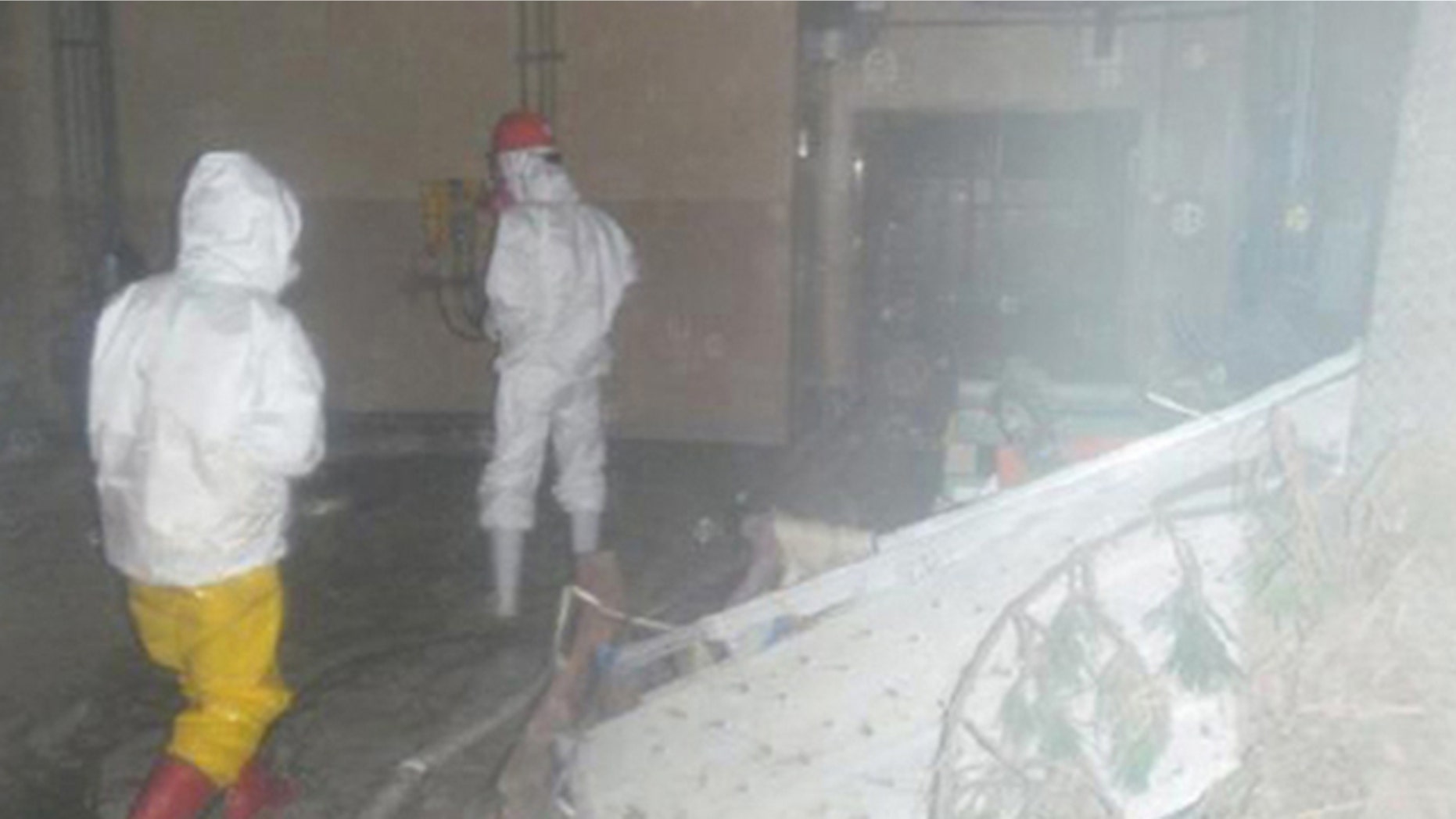 Workers wearing protective suits walk around the entrance of the crippled Fukushima Daiichi Nuclear Power Plant in Fukushima prefecture, northern Japan in this handout photo taken April 8, 2011, and released by Japan's Nuclear and Industrial Safety Agency.