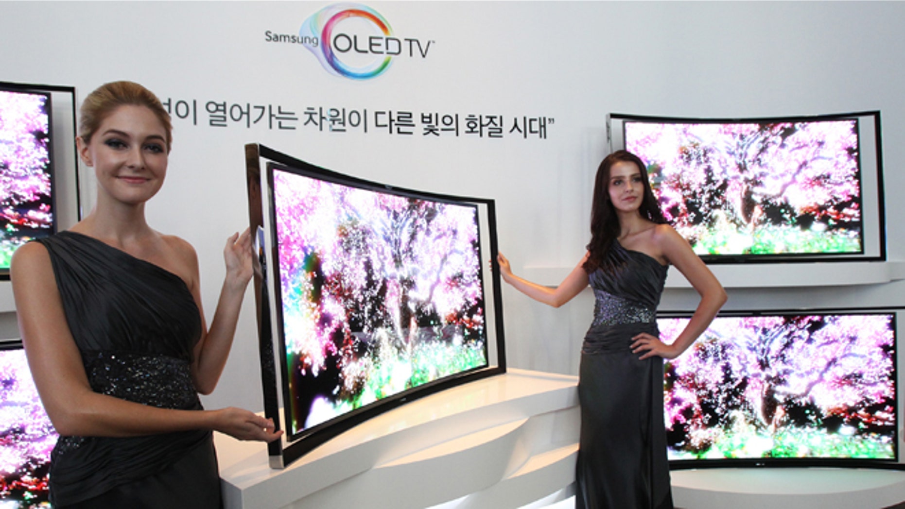 Models pose with a Samsung Electronics Co.'s 55-inch curved OLED TV during a press conference at its headquarters in Seoul, South Korea, Thursday, June 27, 2013. (AP Photo/Ahn Young-joon)