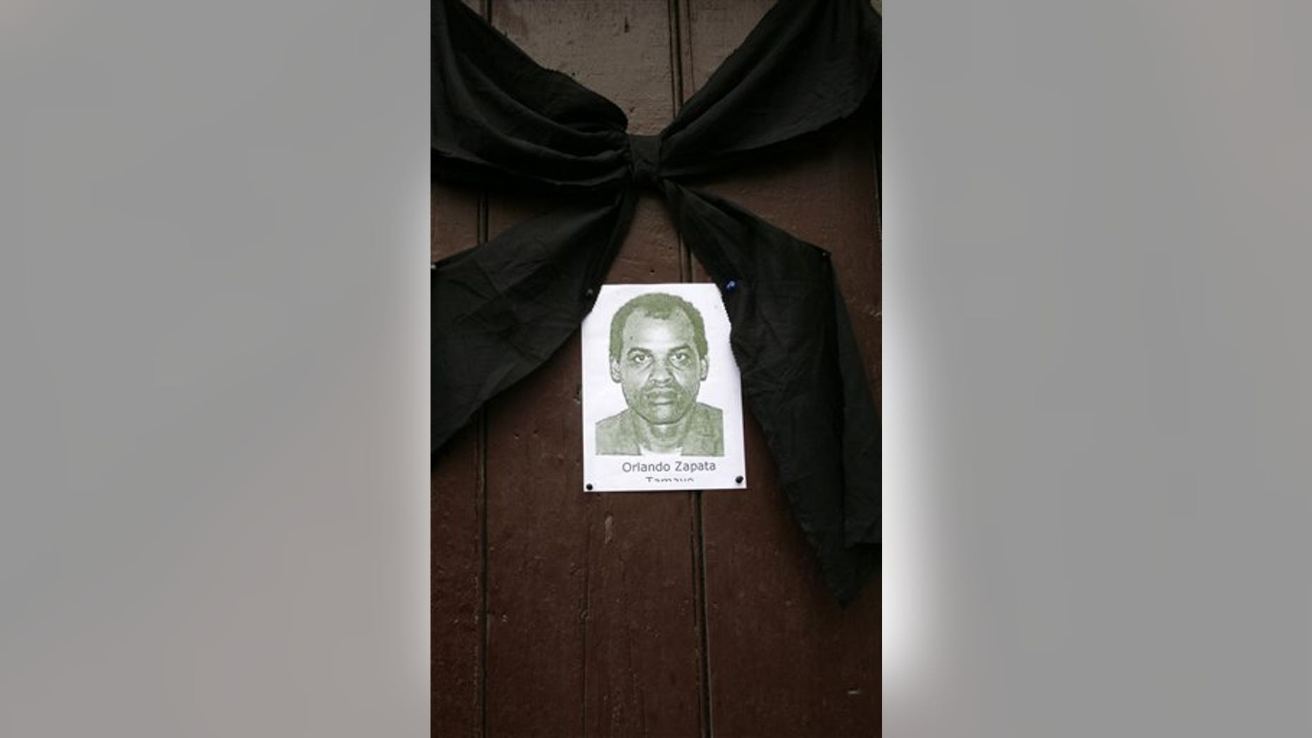 FILE - In this Feb. 24, 2010 file photo, an image of the late Cuban dissident Orlando Zapata Tamayo hangs on a door under a black ribbon in Havana, Cuba. The remains of Tamayo, who died on February 23, 2010 following an 83-day hunger strike, have been exhumed for cremation. Tamayo's mother intends to take the ashes with her on Thursday June 9, 2011 to the United States, which granted her political refuge. (AP Photo/Franklin Reyes, File)