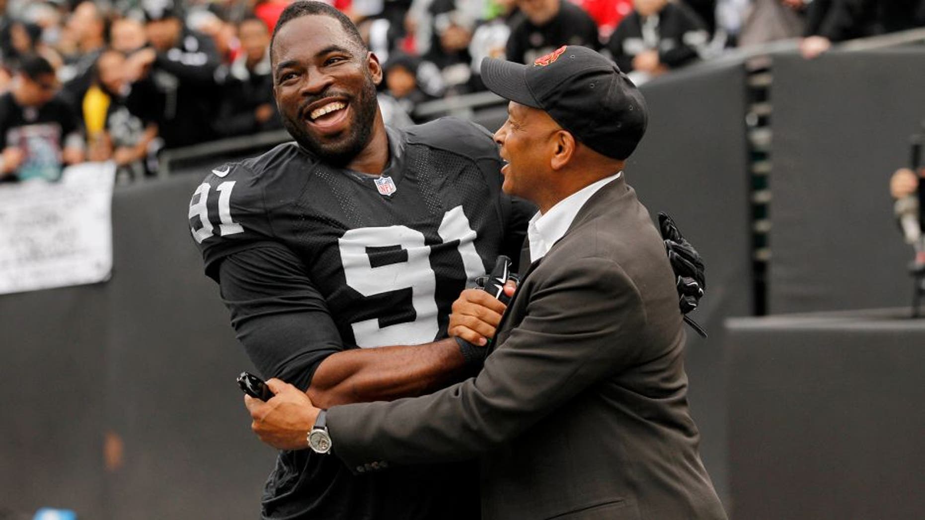Dec 7, 2014; Oakland, CA, USA; Oakland Raiders defensive end Justin Tuck (91) meets with former NFL player Ronnie Lott before the start of the game against the San Francisco 49ers at O.co Coliseum. Mandatory Credit: Cary Edmondson-USA TODAY Sports