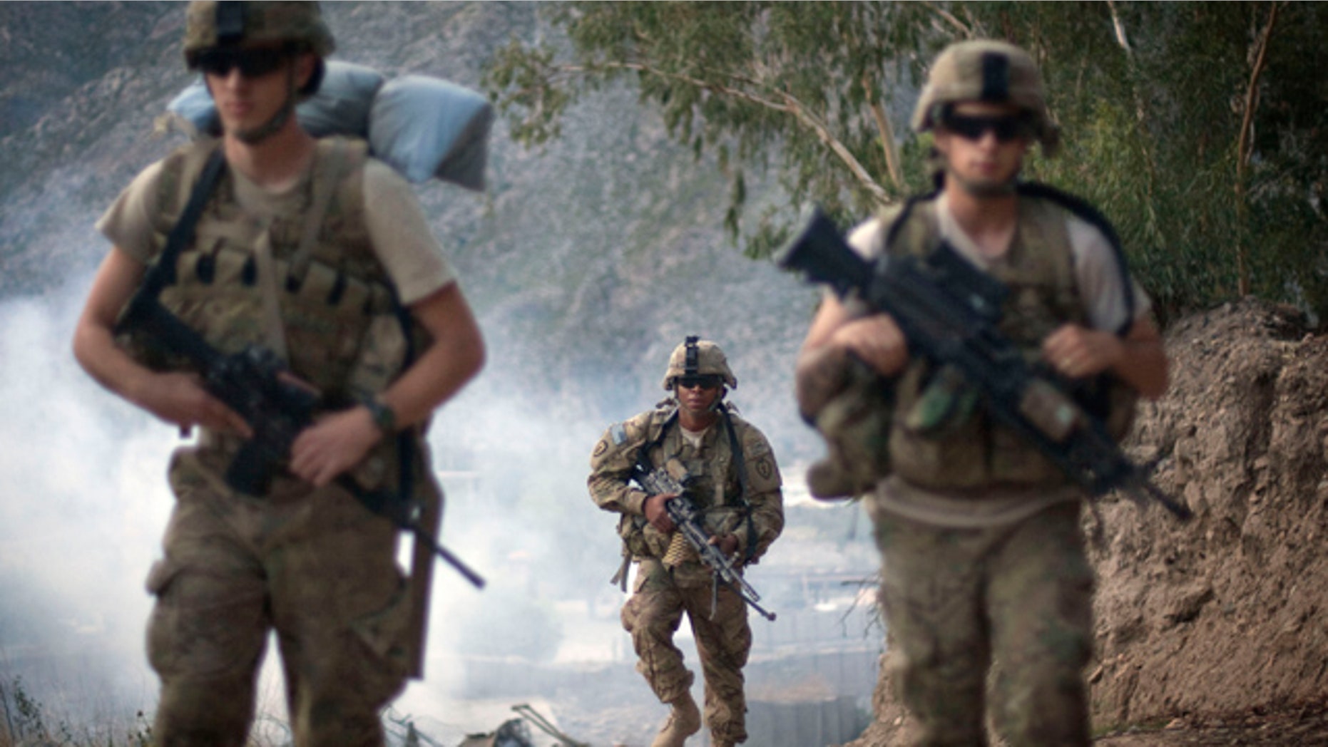 FILE - In this Saturday, Sept. 10, 2011, file photo, U.S. Army Pfc. Garrick Carlton, center, of Sacramento, Calif., hikes past burning rubbish to man a hilltop observation post along with fellow Pfc. Michael Tompkins, of Wadsworth, Ohio, left, and Pfc. Austin D'Amica, of San Diego, at Combat Outpost Monti in Kunar province, Afghanistan. (AP Photo/David Goldman, File)