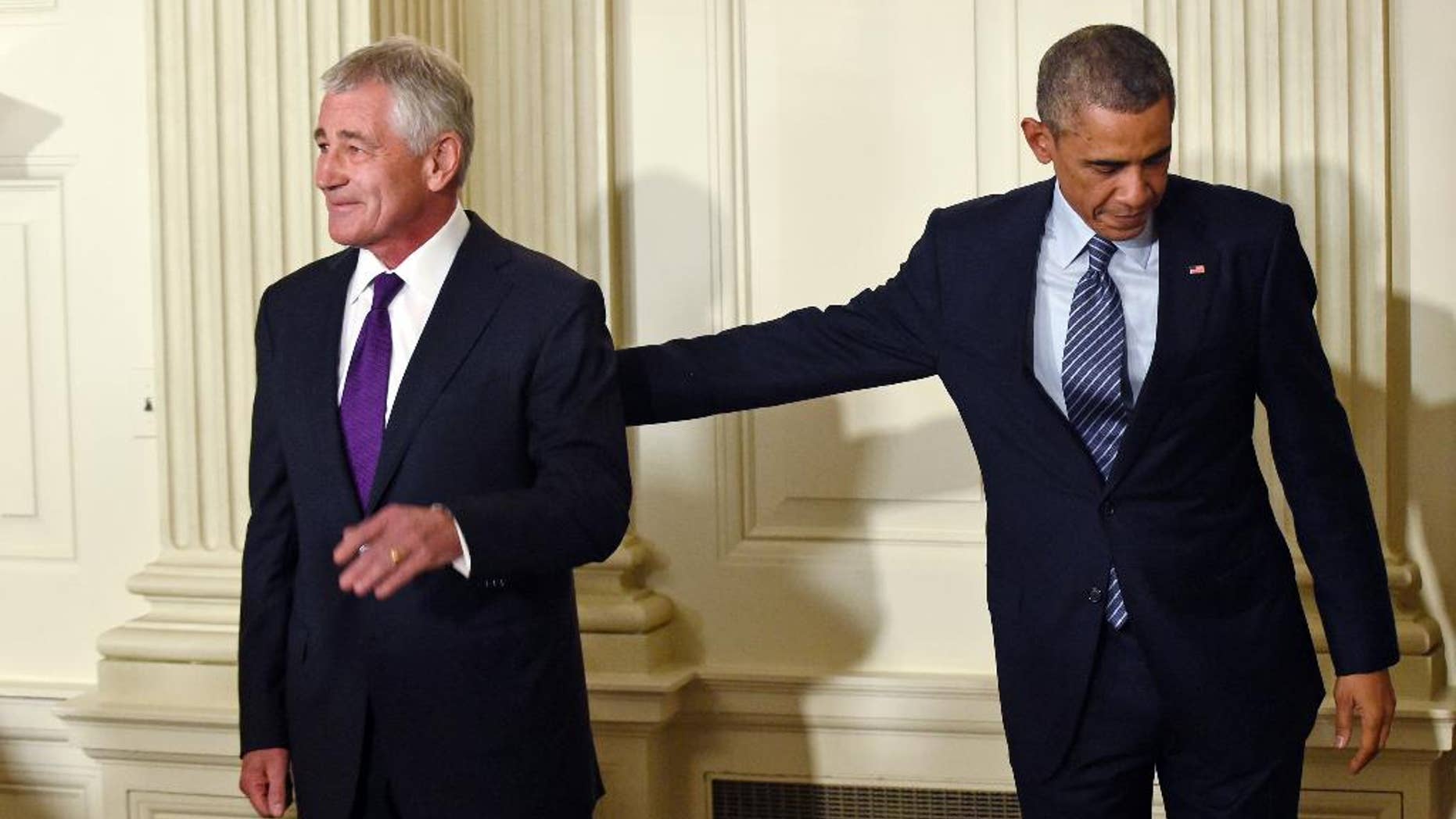 President Barack Obama, left, reaches over to touch Defense Secretary Chuck Hagel, left, following an announcement of Hagel's resignation during an event in the State Dining Room of the White House in Washington, Monday, Nov. 24, 2014. Hagel is stepping down under pressure from Obama's Cabinet, senior administration officials said Monday, following a tenure in which he has struggled to break through the White House's insular foreign policy team. (AP Photo/Susan Walsh)