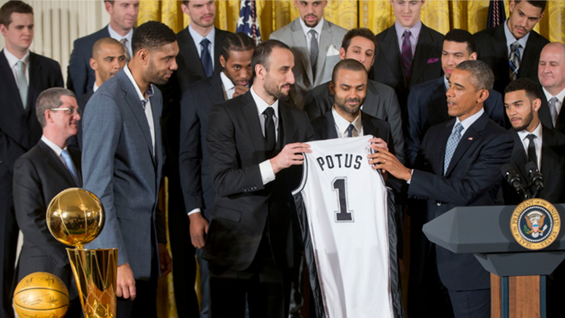 President Barack Obama accepts a San Antonio Spurs team basketball jersey from San Antonio Spurs team members, from left, forward Tim Duncan of the Virgin Islands, guard Manu Ginobili of Argentina, and guard Tony Parker of France, as the president honored the 2014 NBA Champions the San Antonio Spurs basketball team during a ceremony in the East Room White House in Washington, Monday, Jan. 12, 2015. (AP Photo/Pablo Martinez Monsivais)
