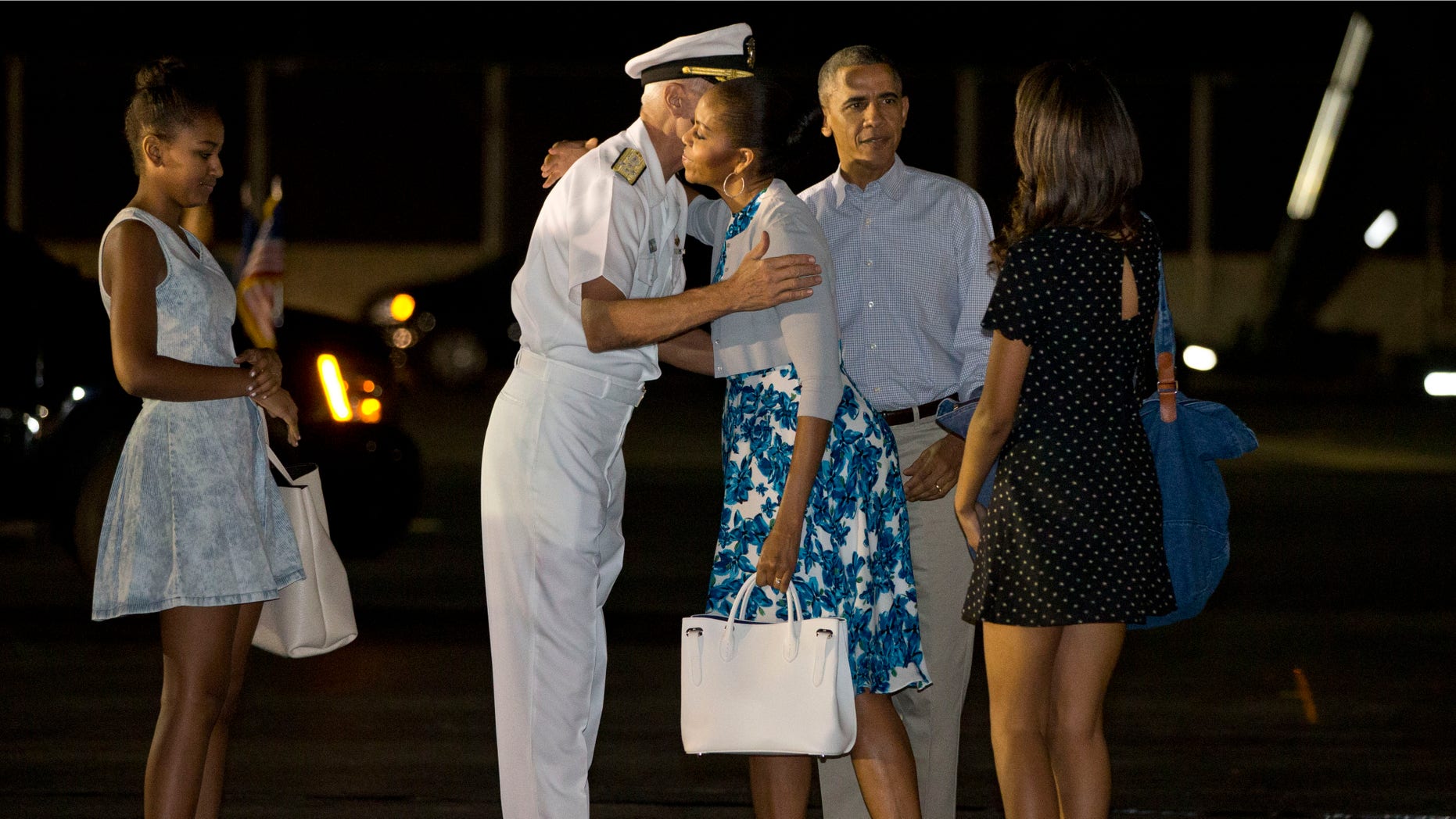 Dec. 20, 2014: First lady Michelle Obama hugs Admiral Samuel Locklear III, Commander, U.S. Pacific Command, with daughter Sasha Obama, left, and Malia Obama, far right, and President Barack Obama as the first family arrives at Pearl Harbor