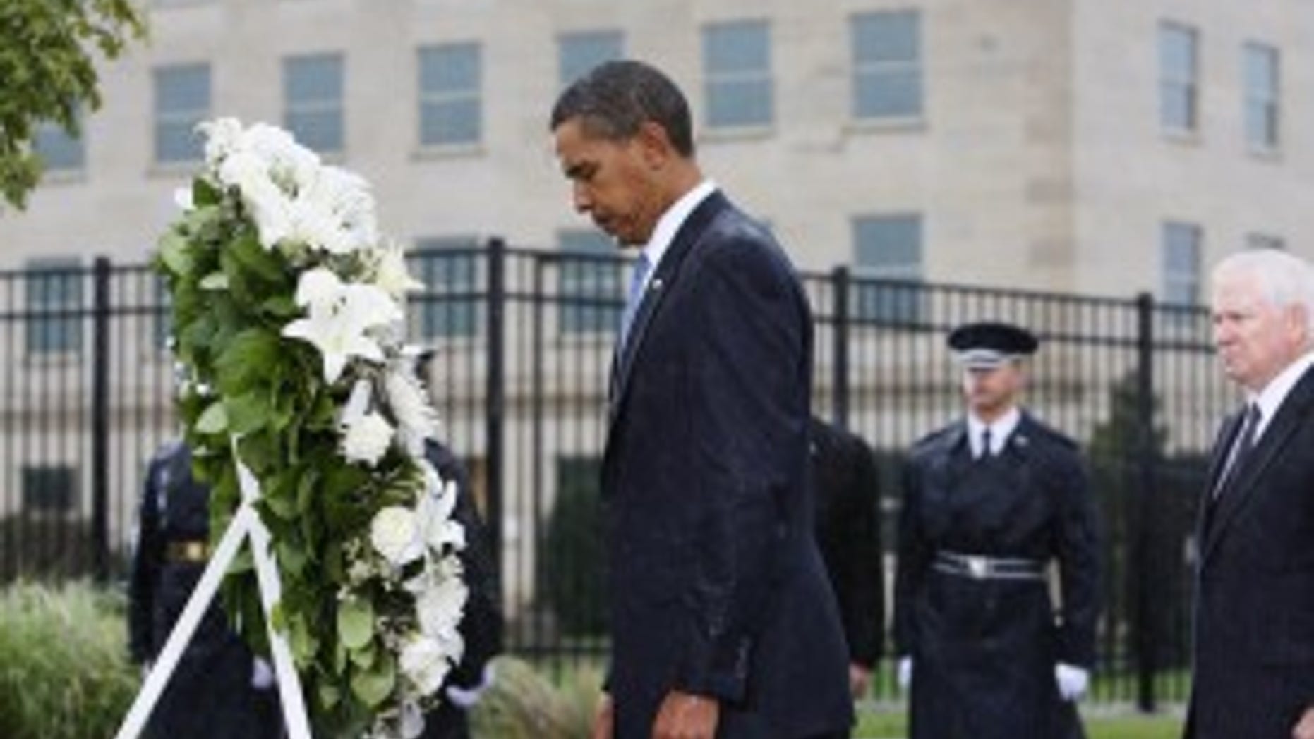 Standing in a steady rain, President Barack Obama bows his head as he lays a wreath at the Pentagon Memorial, marking the eighth anniversary of the Sept. 11 attacks, Friday, Sept. 11, 2009, at the Pentagon. Defense Secretary Robert Gates is at right. (AP Photo/Charles Dharapak)