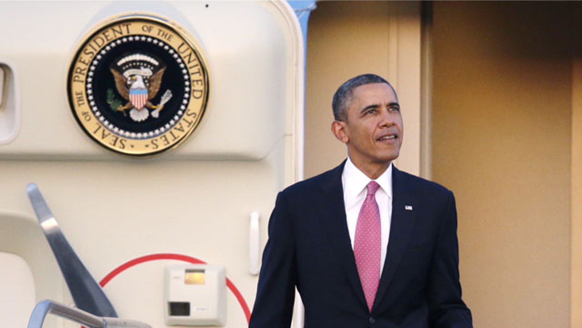 November 24, 2013: President Barack Obama briefly glances up toward the sunset after arriving at Seattle-Tacoma International Airport in Seattle. (AP Photo)