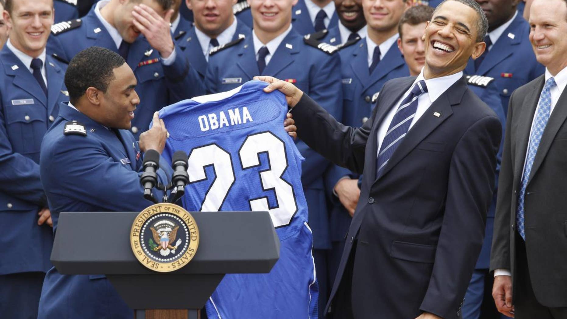 Air Force Academy's defensive back Reggie Rembert presents President Barack Obama with a personalized jersey as head coach Troy Calhoun, right, and running back Jared Tew, top left, look on during a ceremony in the Rose Garden of the White House in Washington, Monday, April 18, 2011, presenting the 2010 Commander-in-Chief Trophy to the Air Force Academy football team. (AP Photo/Charles Dharapak)