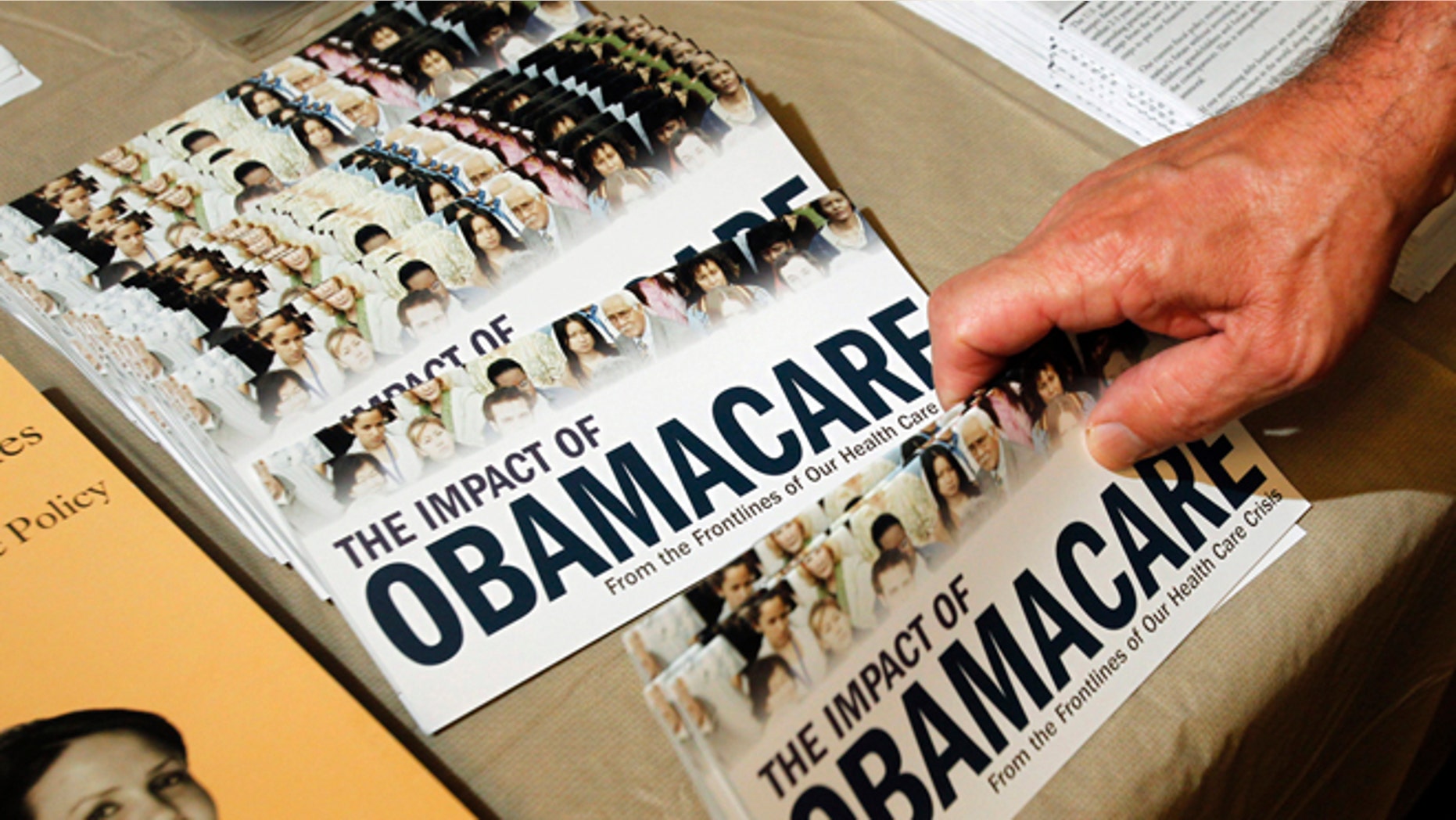 FILE: July 2, 2013: A Tea Party member reaches for a pamphlet on the impact of ObamaCare, at a rally in Littleton, New Hampshire.