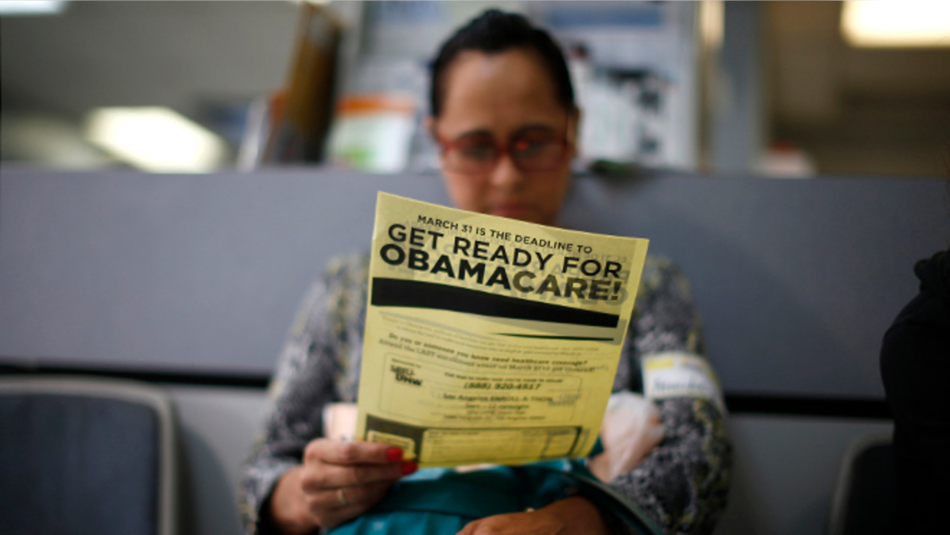 FILE: March 27, 2014: A woman reads a leaflet at a ObamaCare enrollment event in Cudahy, California