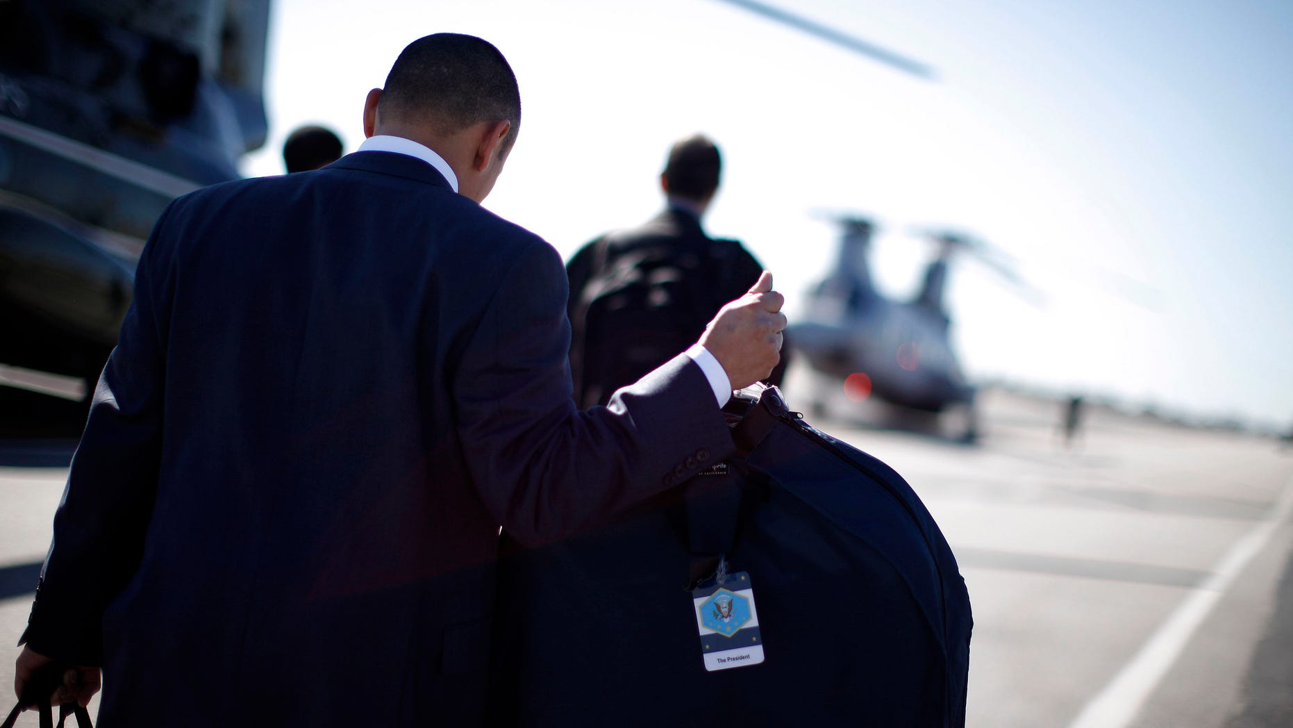 FILE: February 16, 2012. A White House staffer carries a suit bag labelled for President Obama at John Wayne Airport in Orange County, Calif.