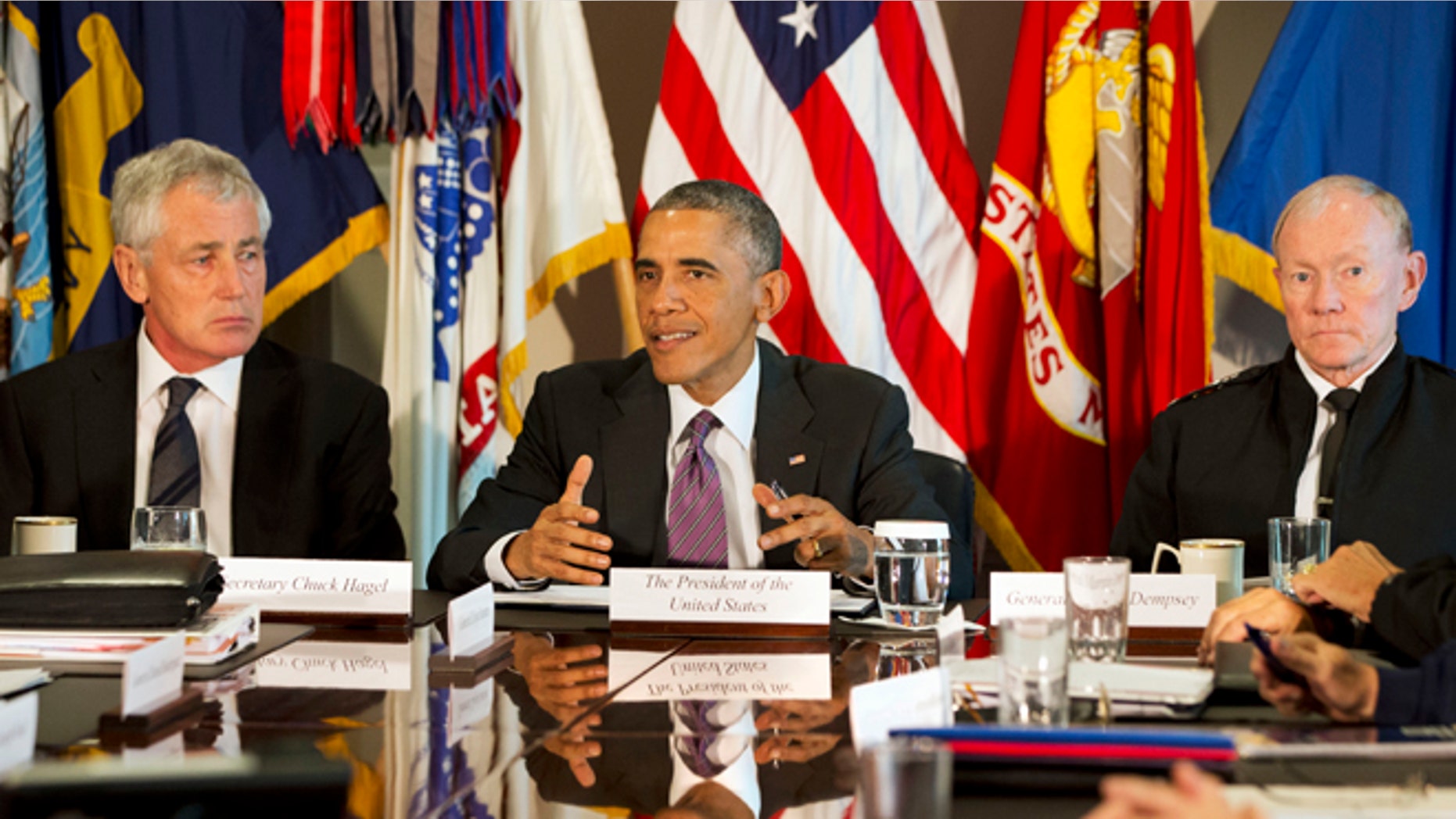 In this Wednesday, Oct. 8, 2014 photo, President Barack Obama, flanked by Defense Secretary Chuck Hagel, left, and Joint Chiefs Chairman Gen. Martin Dempsey, speaks to the media at the conclusion of a meeting with senior military leadership at the Pentagon.