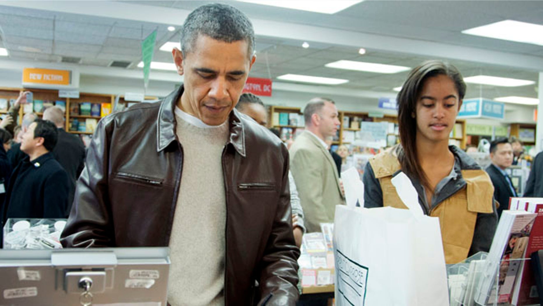 Saturday, Nov. 30, 2013: President Obama, with daughters Sasha, center partially hidden, and Malia, pays for his purchase at the Politics and Prose bookstore in Washington, D.C.