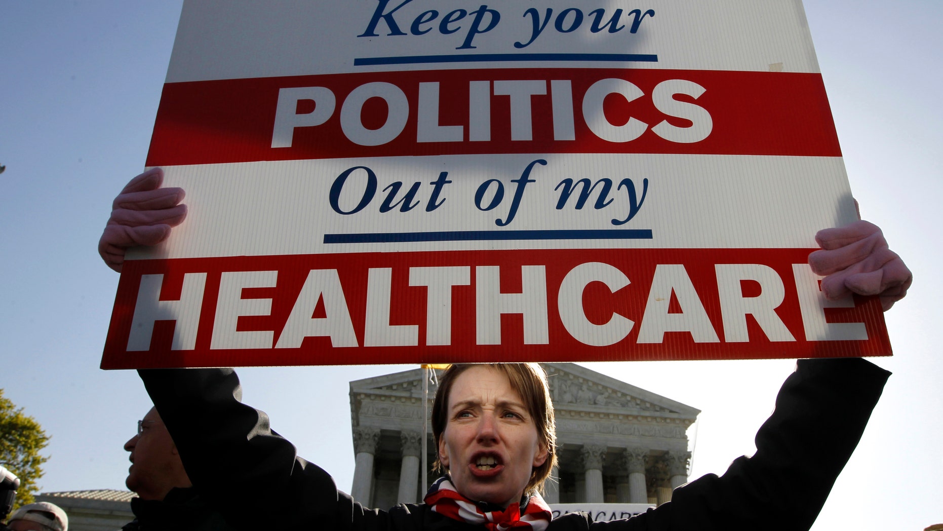 FILE - In this March 27, 2012, file photo, Amy Brighton of Medina, Ohio, who opposes health care reform, rallies in front of the Supreme Court in Washington. Health care was the defining political battle of President Barack Obamas first term, and _ after the economy_ it remains his most complicated policy challenge at home, central to his place in history.(AP Photo/Charles Dharapak, File)