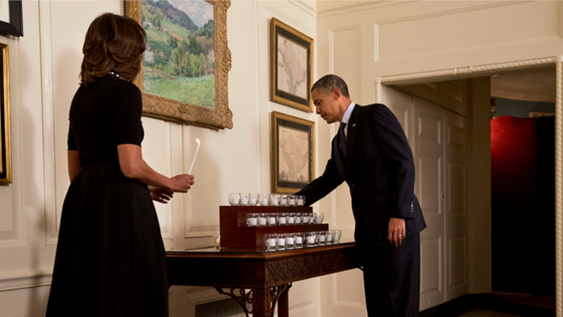 Saturday, Dec. 14, 2013: President Obama and first lady Michelle Obama light candles in honor of the Newtown shooting victims, in the Map Room of the White House in Washington, D.C.
