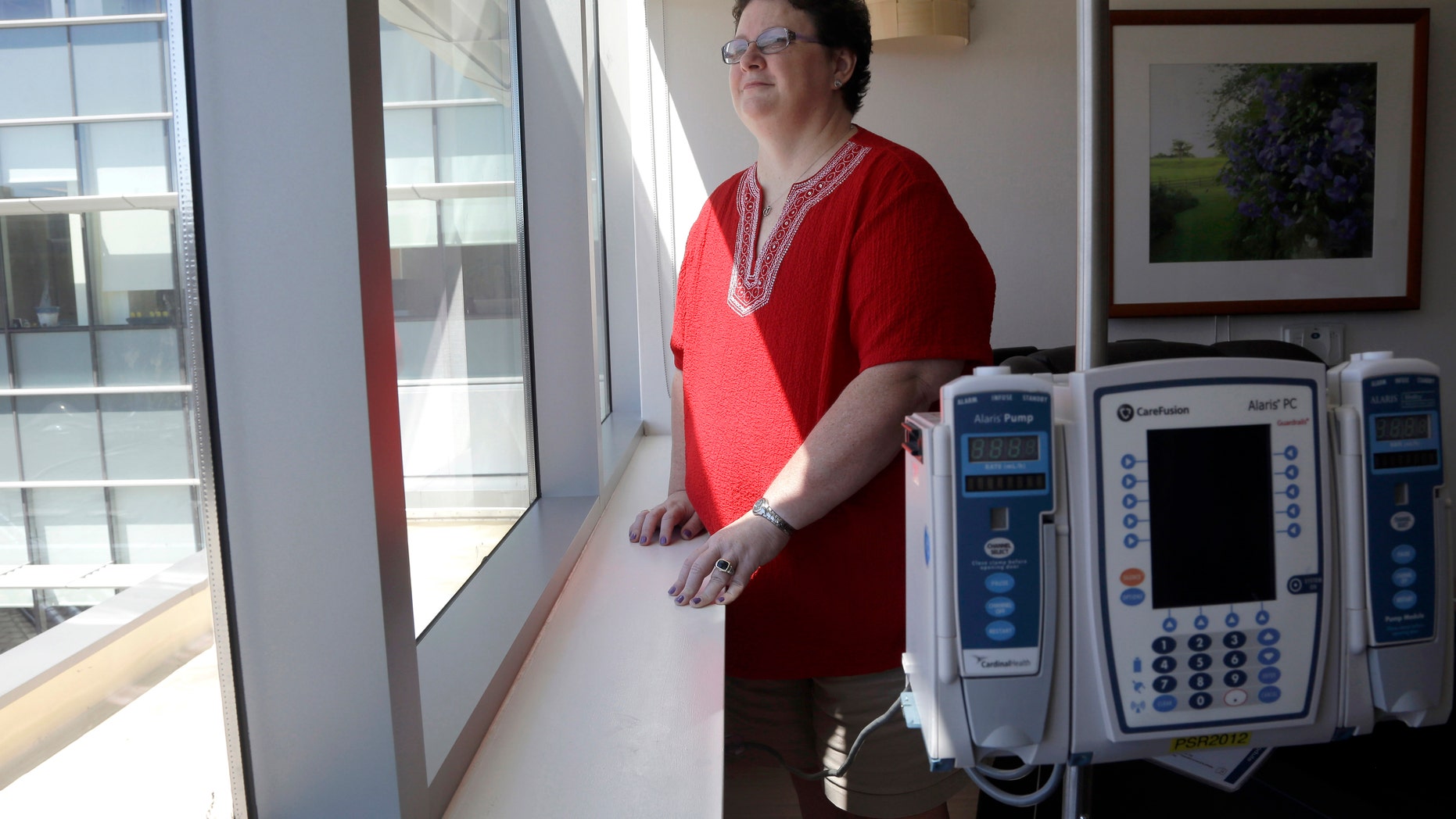 In this Thursday, Sept. 5, 2013 photo, Tracy Smith looks out of a window at the infusion center at Duke Cancer Center in Durham, N.C. Smith was treated at Duke in 2011 for breast cancer that had spread to more than a dozen lymph nodes. Doctors gave her full chemo doses based on her weight. Three times, high fevers put her in the hospital, and one infusion was cut short because doctors thought it was causing wheezing and possible lung damage. But she resumed and finished the intended treatment and has been cancer-free since then. (AP Photo/Gerry Broome)