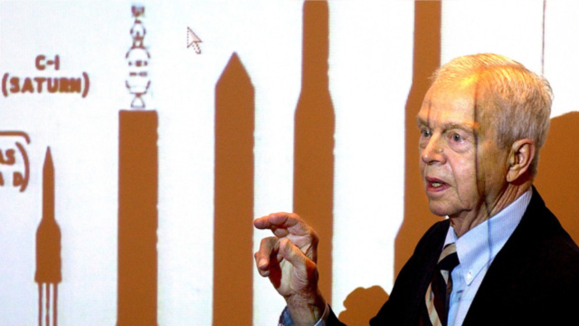 File-This Oct. 9, 2003, file photo shows John C. Houbolt explaining the size of different rockets required to launch various methods for landing on the moon at Grainger Engineering Library in Urbana, Ill. (AP Photo/News-Gazette, John Dixon, File)