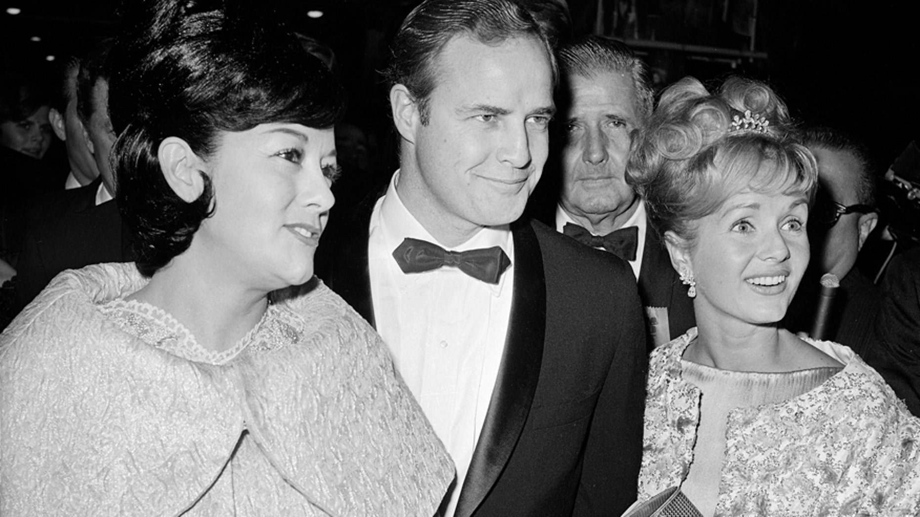 FILE-This Nov. 15, 1962 file photo shows Marlon Brando, his wife, Mexican actress Movita Castaneda, left, and actress Debbie Reynolds, right, arriving for the West Coast premiere of "Mutiny on the Bounty" at the Hollywood Egyptian Theater in Los Angeles. Castaneda, the dark-haired actress who met Brando on a movie set and later married him and had two of his children died Thursday, Feb. 12, 2015 at a Los Angeles rehabilitation center after being treated for a neck injury. The Los Angeles Times says Castaneda was believed to be 98.