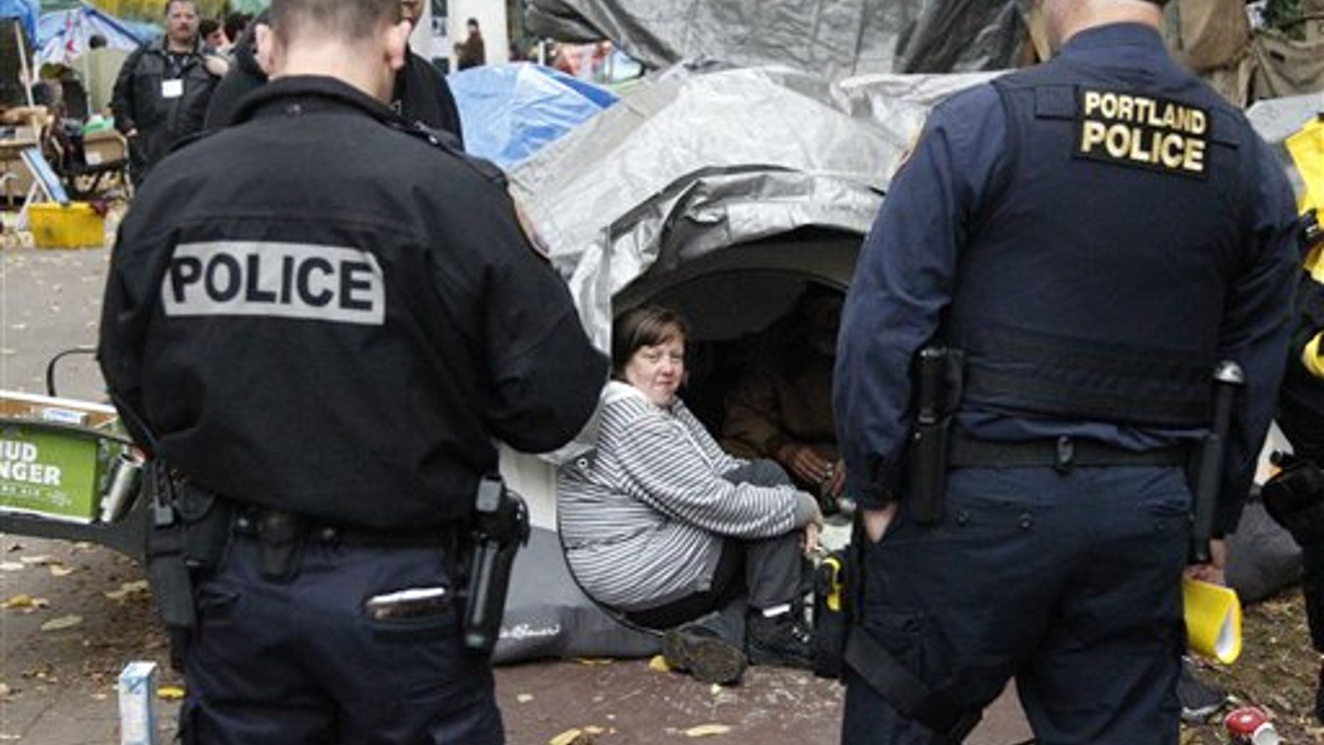 Nov. 11, 2011: Erin Robertson sits in the doorway of a tent while Portland police look on at the Occupy Portland encampment.