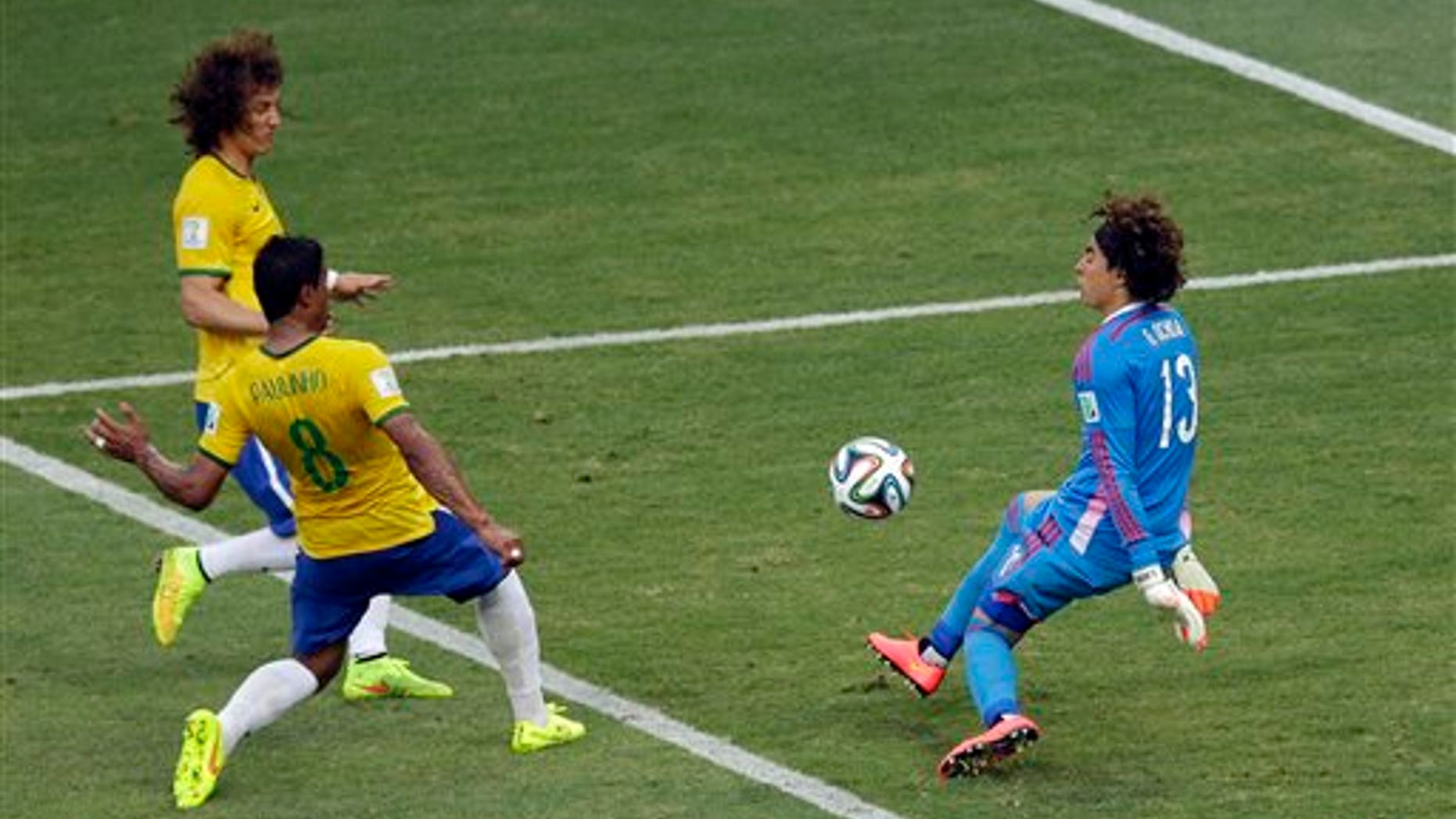 Ochoa deflects a ball as David Luiz and Paulinho approach during the group A World Cup soccer match June 17, 2014.