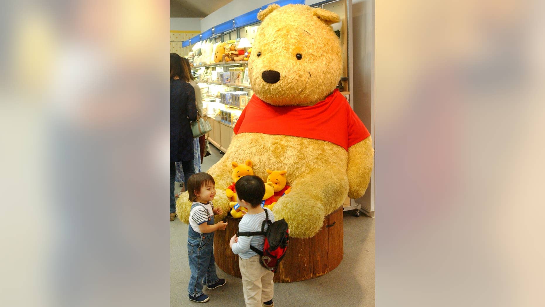 FILE - Two boys chat in front of a giant stuffed doll of Winnie-The-Pooh at the "World of Winnie-The-Pooh" exhibition at a Tokyo department store in this April 24, 2002 file photo. Officials in a Polish town have opposed a proposition to name a playground after Winnie-the-Pooh due to the bear's unclear gender and immodest clothing. (AP Photo/Koji Sasahara, File)