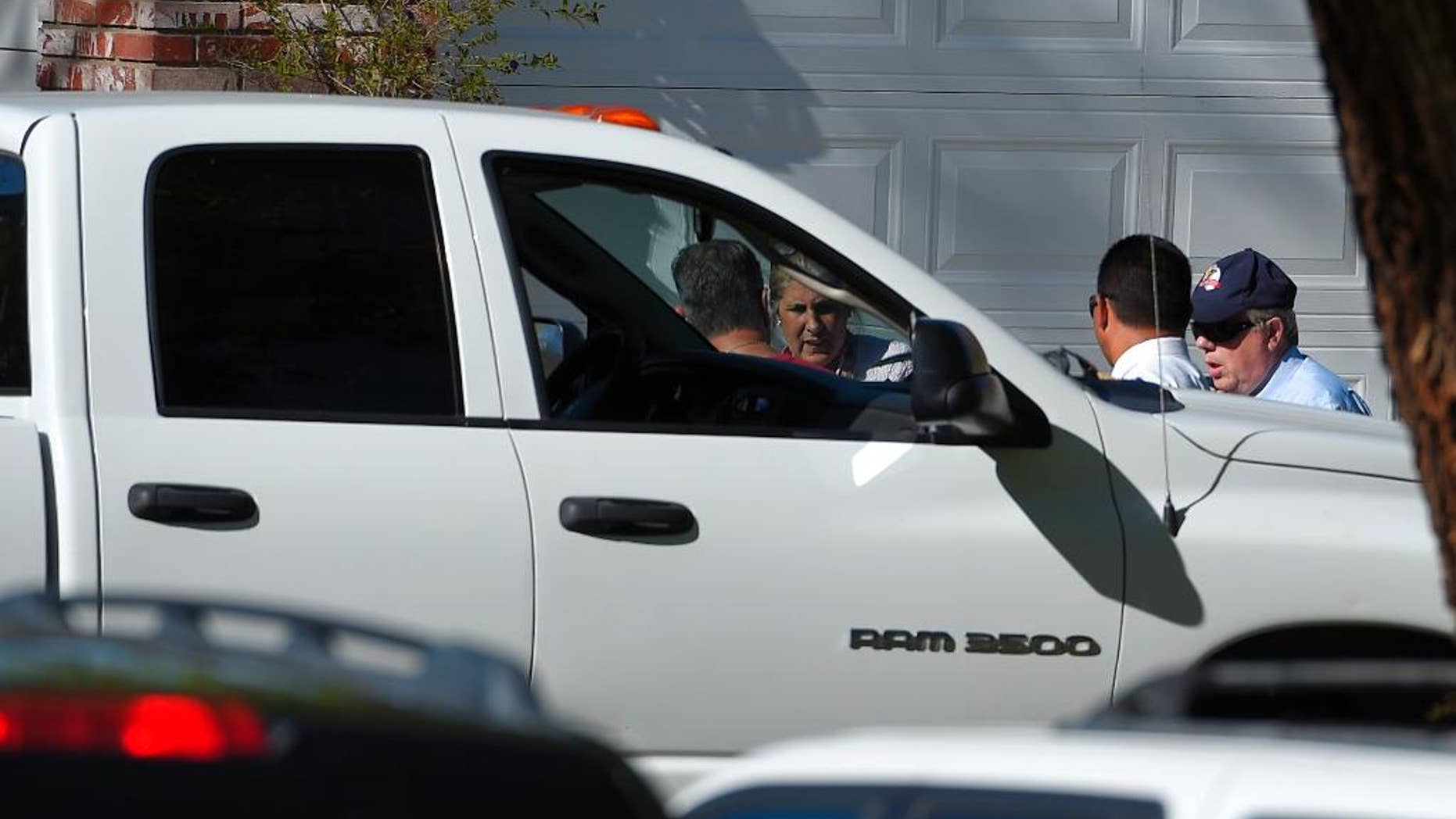 An off-duty Los Angeles police officer, left, talks to investigators next to his vehicle at the scene of an officer involved shooting, Sunday, March 29, 2015, in Santa Clarita, Calif. Authorities have detained a man suspected of shooting at an off-duty Los Angeles police officer from a car before fleeing the scene at a suburban neighborhood in northern Los Angeles county. (AP Photo/Mark J. Terrill)