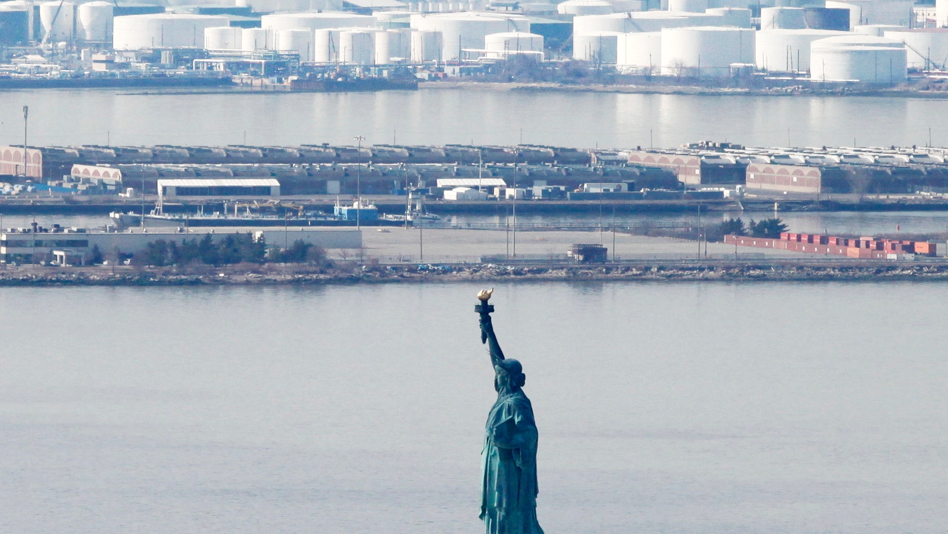 March 15: The Statue of Liberty stands in New York Harbor with an oil storage facility behind it in New York. Oil prices fell with concerns over Japan's economy, but they rebounded March 16 as demand for energy was high amid world crises.