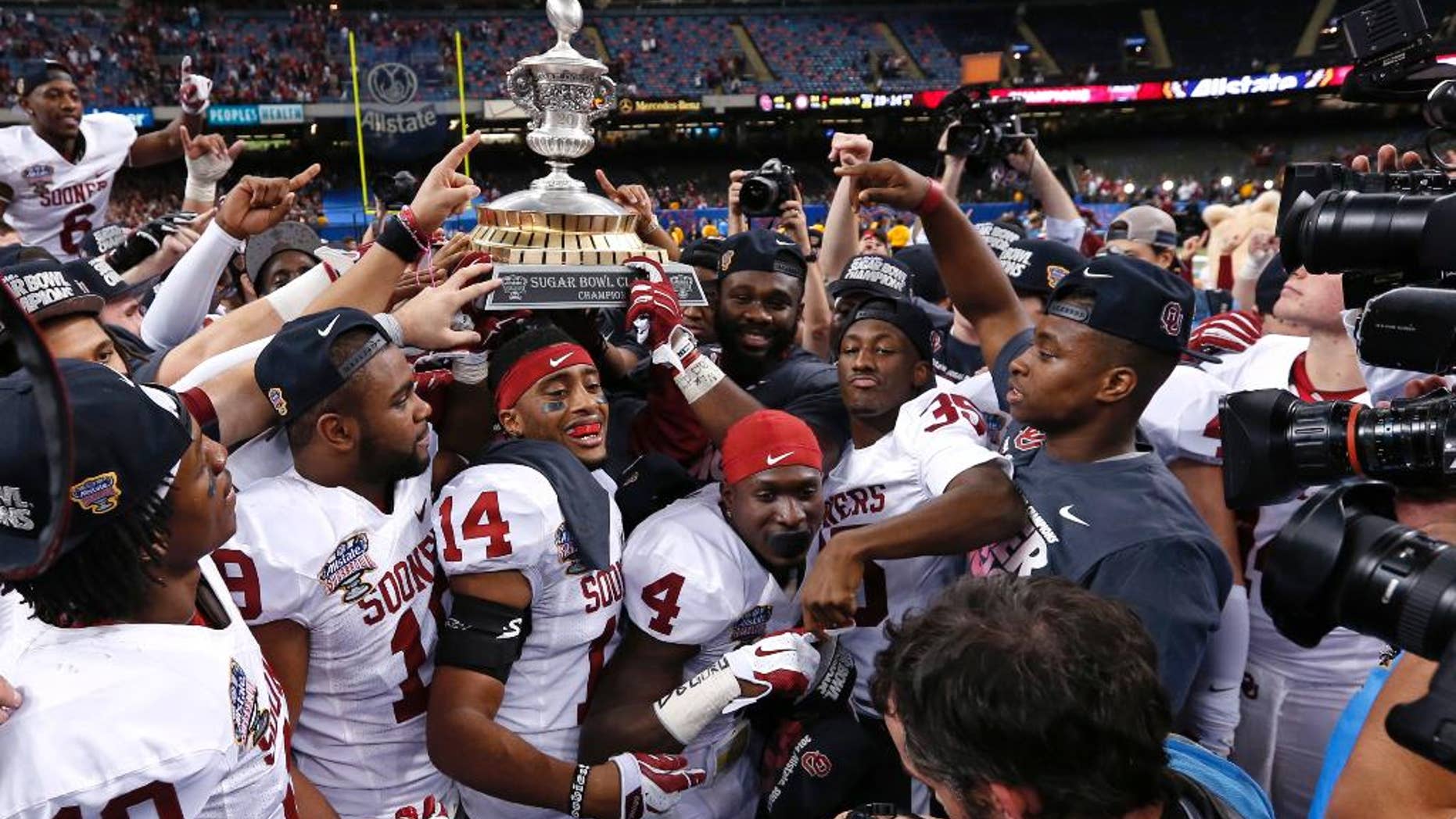 FILE - In this Jan. 3, 2014 file photo, Oklahoma holds up the Sugar Bowl trophy after defeating Alabama 45-31 in the NCAA college football matchup in New Orleans. It now seems like forever since Oklahoma defeated Alabama in the Sugar Bowl. The hype around the program has been building ever since. (AP Photo/Rusty Costanza, File)