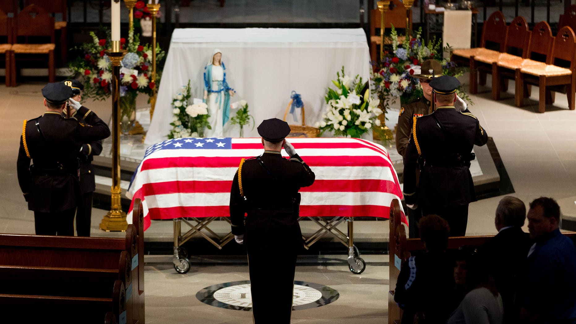 Omaha police officers salute before removing the flag from the top of the casket before the funeral service for Omaha police detective Kerrie Orozco, Tuesday, May 26, 2015 at St. John's Catholic Church at Creighton University in Omaha, Neb. Orozco, 29, was shot and killed May 20, 2015 in Omaha. (Matt Miller/The World-Herald via AP, Pool)