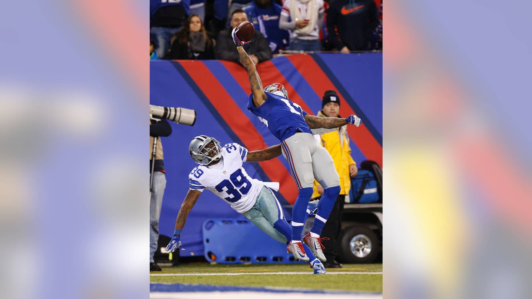FILE - In this Nov. 23, 2014, file photo, New York Giants wide receiver Odell Beckham Jr. (13) makes a one-handed catch for a touchdown against Dallas Cowboys cornerback Brandon Carr (39) in the second quarter of an NFL football game in East Rutherford, N.J. The one-handed catch by Odell Beckham Jr. that became the most talked-about play from Sunday, Nov. 23, 2014, did more than just boost his standing with the Giants, it paid off a routine growing popular among many skill players of practicing the impractical, one-handed circus grab. (AP Photo/Kathy Willens, File)