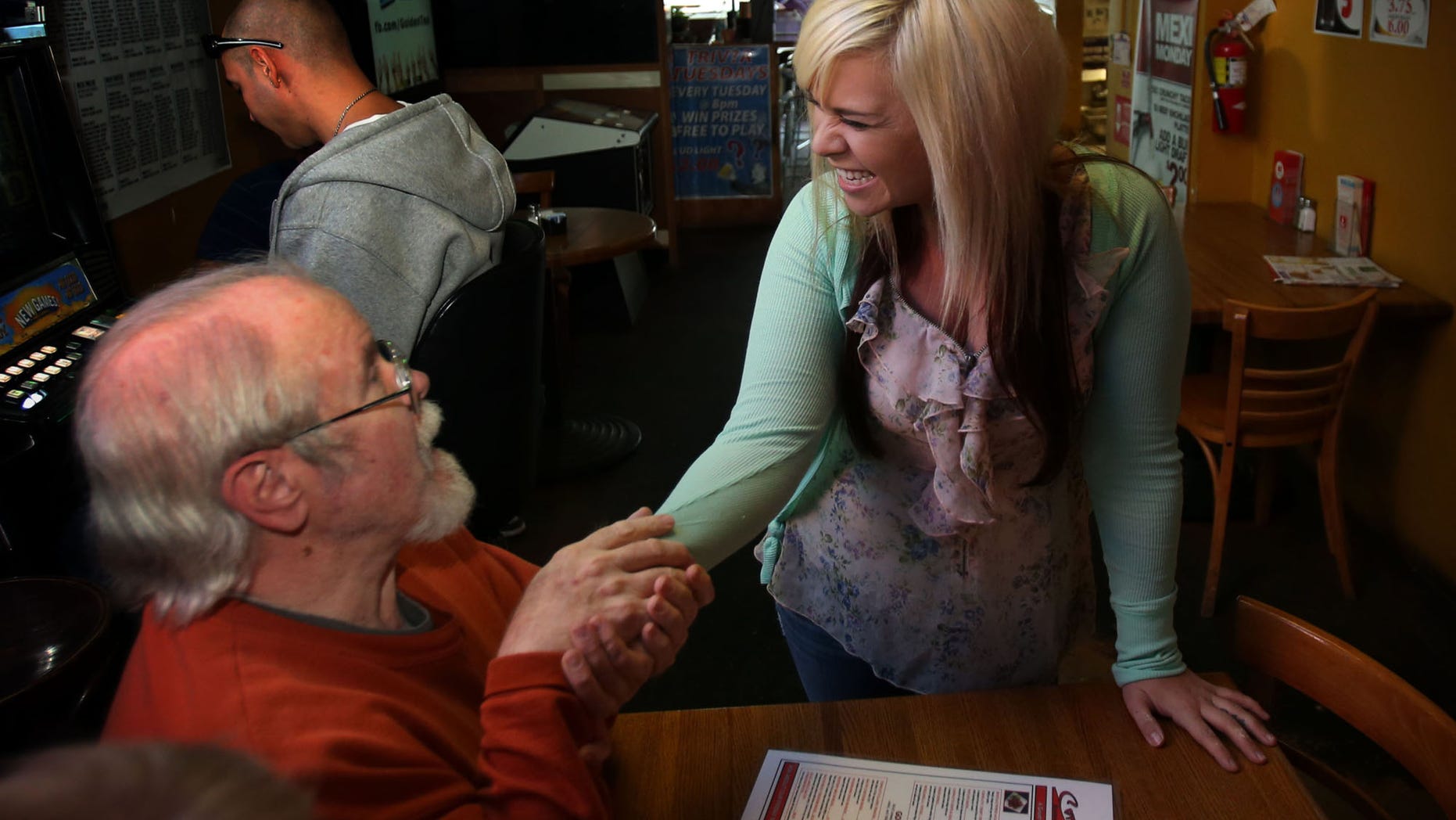Customer Jerry Arnett, left, congratulates Aurora Kephart, a bartender in Springfield, Ore., Friday Oct. 4, 2013 after learning that she indirectly received a $17,500 tip when one of her customers happened to give her a winning lottery ticket this week. The Oregon Lottery reports that one of Kephart's regular customers at Conways Restaurant gave her a couple Keno tickets on Tuesday and when she checked one was a big winner. (AP Photo/The Register-Guard, Chris Pietsch)