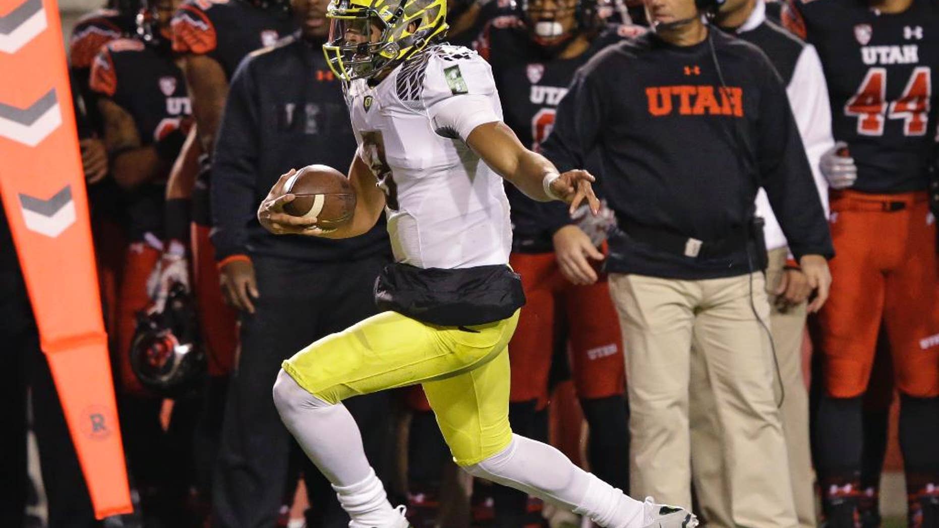 Utah defensive back Marcus Williams (20) tackles Oregon quarterback Marcus Mariota (8) as stretches to make a first down in the first quarter during an NCAA college football game Saturday, Nov. 8, 2014, in Salt Lake City. (AP Photo/Rick Bowmer)