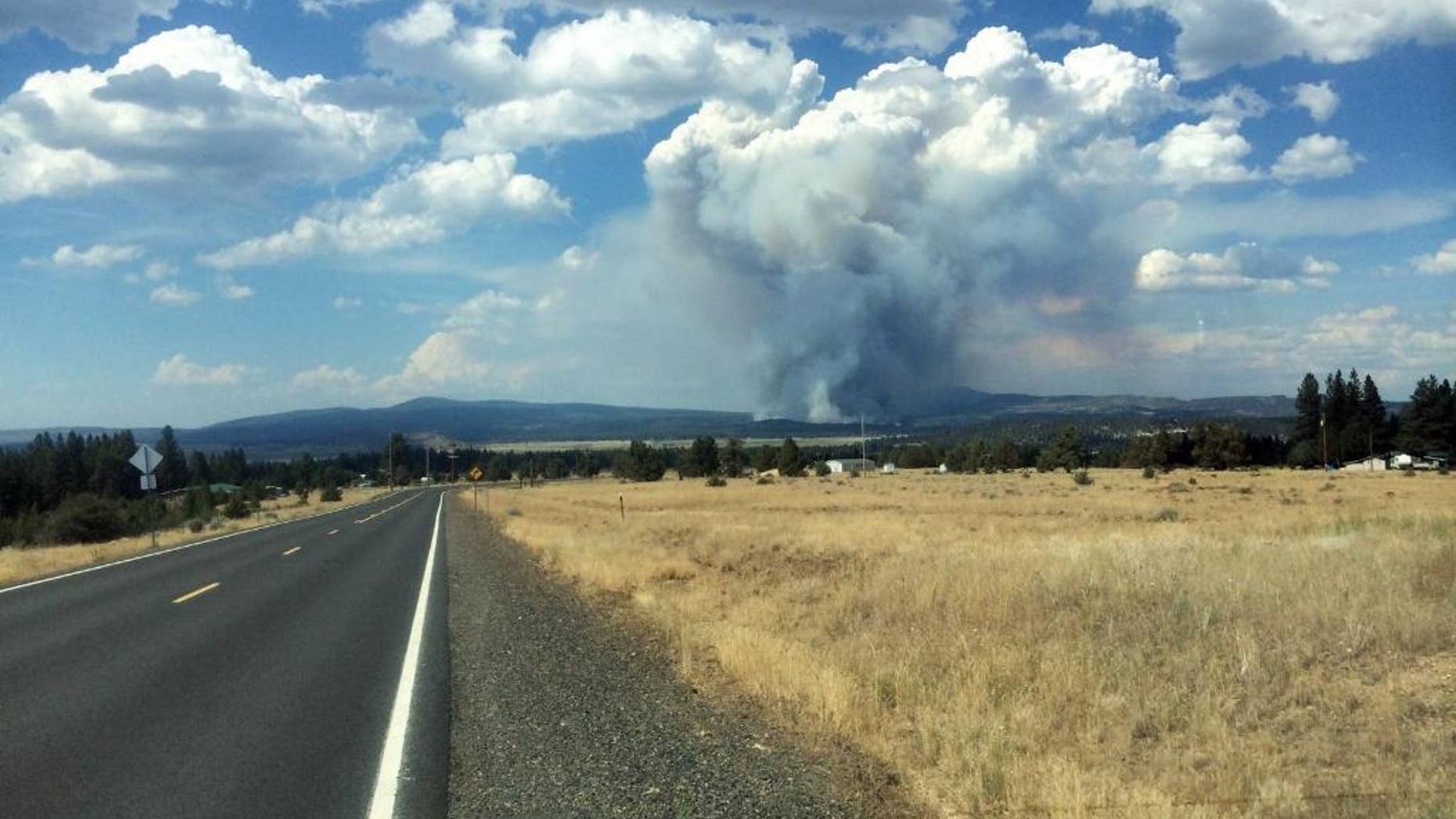 In this photo provided by South Central Oregon Fire Management Partnership, smoke from a fire is seen Sunday, July 13, 2014, near Moccasin Hill, Ore. Officials say a fast-growing wildfire in southern Oregon has destroyed homes and forced dozens of evacuations. (AP Photo/South Central Oregon Fire Management Partnership)