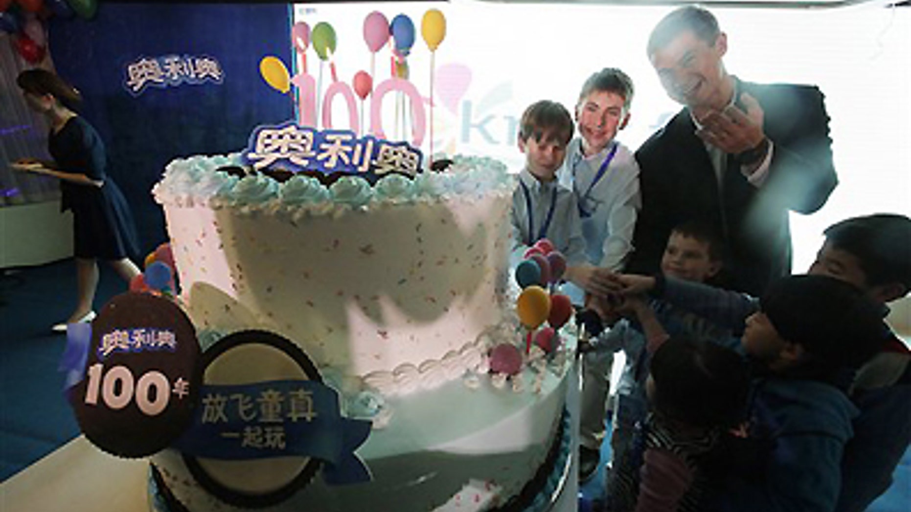 Tuesday March 6, 2012: Shawn Warren, president of Kraft Foods China, back row right, and children cut the birthday cake for Oreo cookie's 100th anniversary celebration in Shanghai, China.