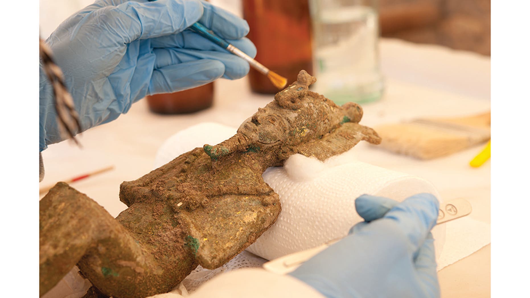 Researchers carefully conserve an Osiris statuette found within the favissa. It's possible the statue of the god Ptah was placed with the Osiris statuettes because Osiris was the god of rebirth.