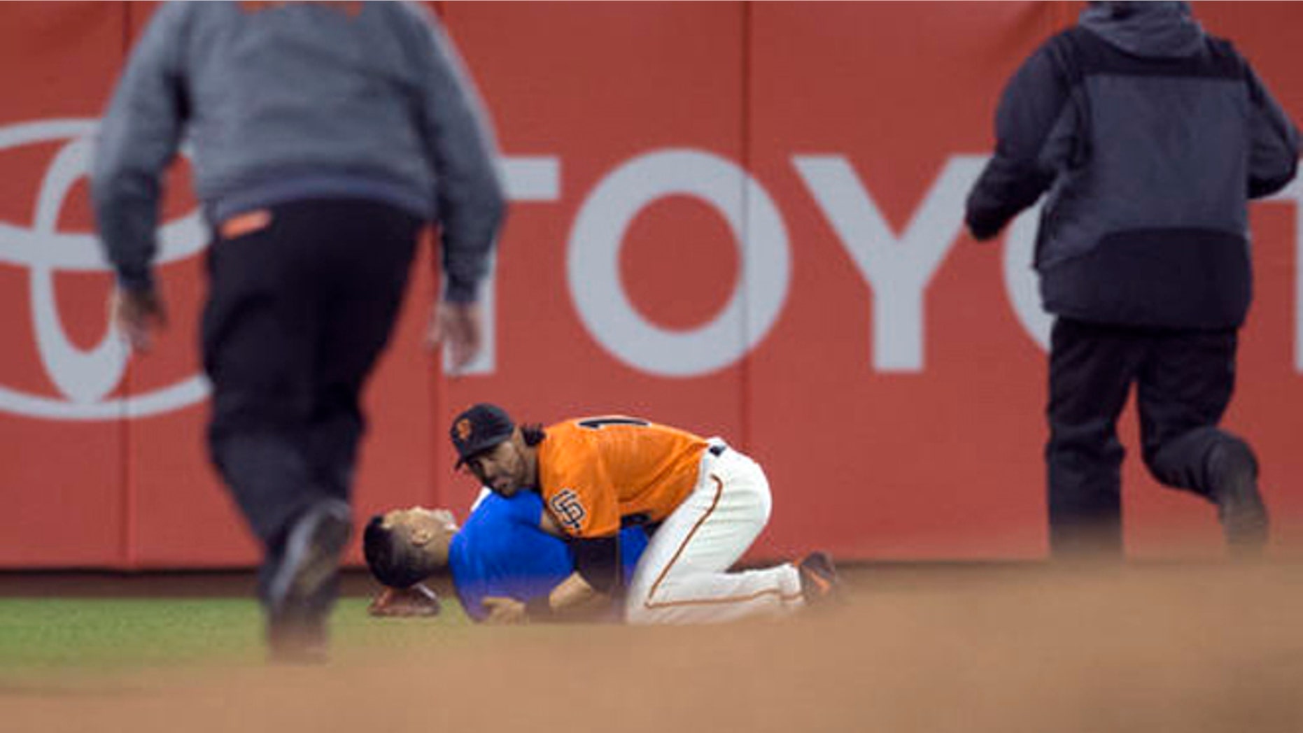 San Francisco Giants Angel Pagan (16) holds down a man who ran onto the field during the fourth inning of the Giants' baseball game against the Los Angeles Dodgers, Friday, Sept. 30, 2016, in San Francisco. (AP Photo/D. Ross Cameron)