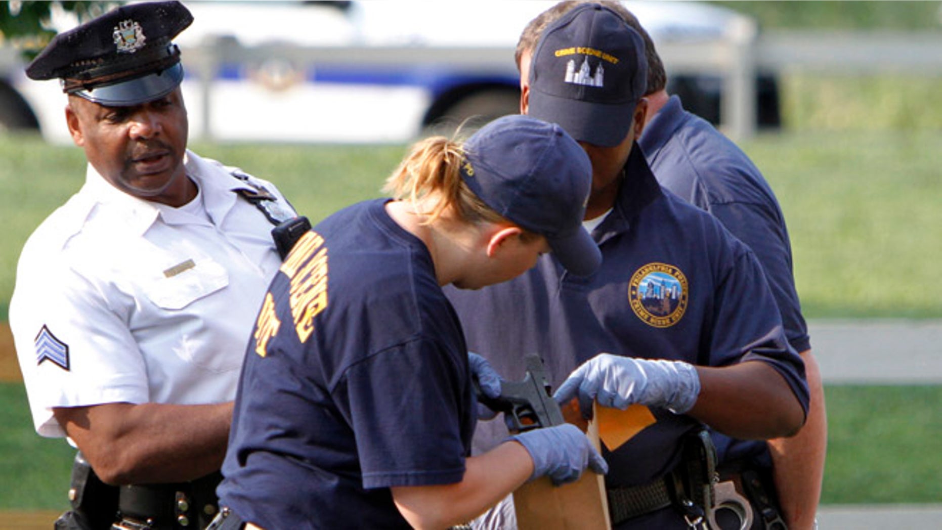 Aug. 18, 2102: Crime scene investigators look over an officer's handgun after the off-duty Philadelphia police officer was shot and mortally wounded.